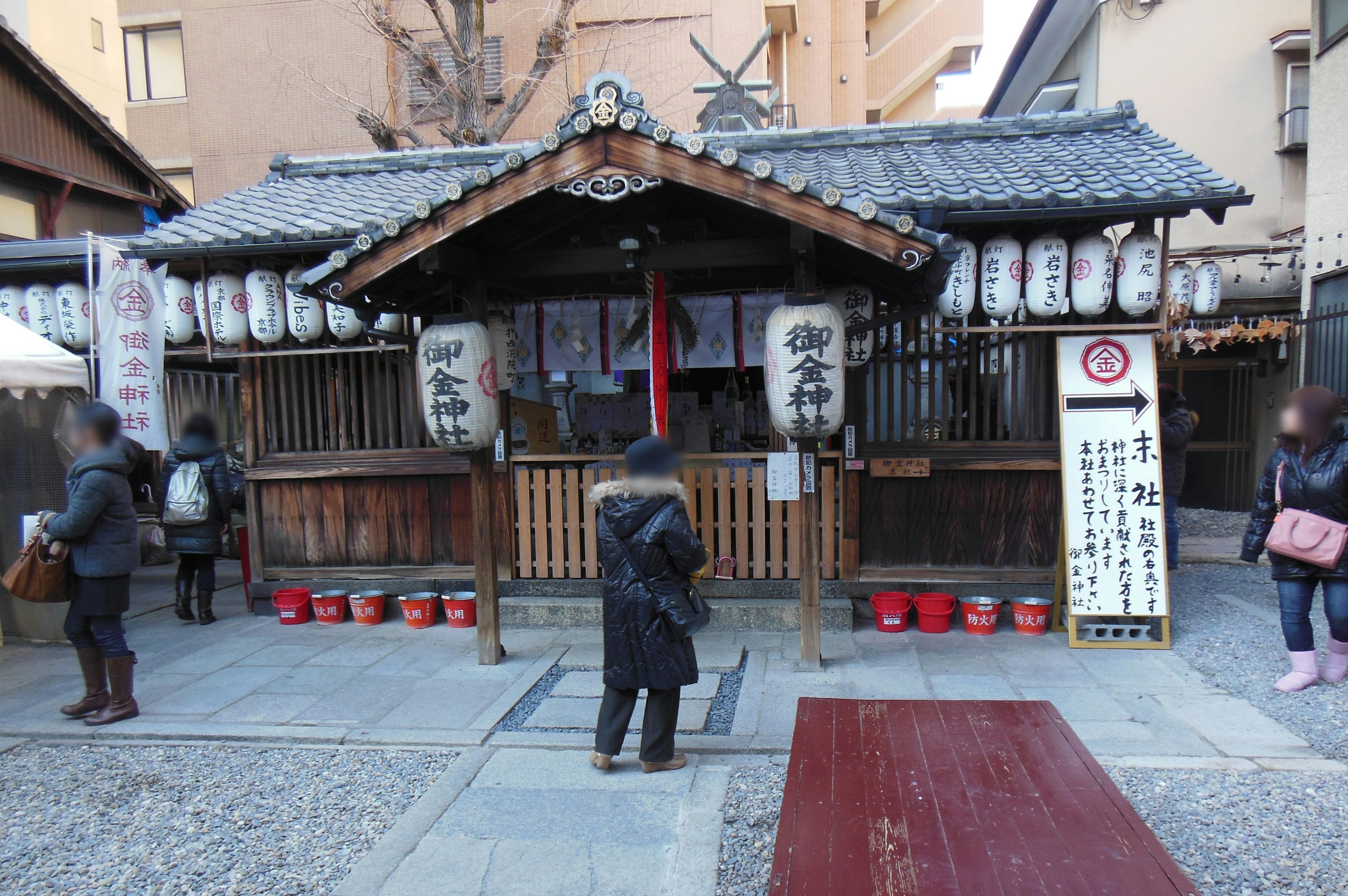 Traditional shrine exterior with hanging lanterns and visitors