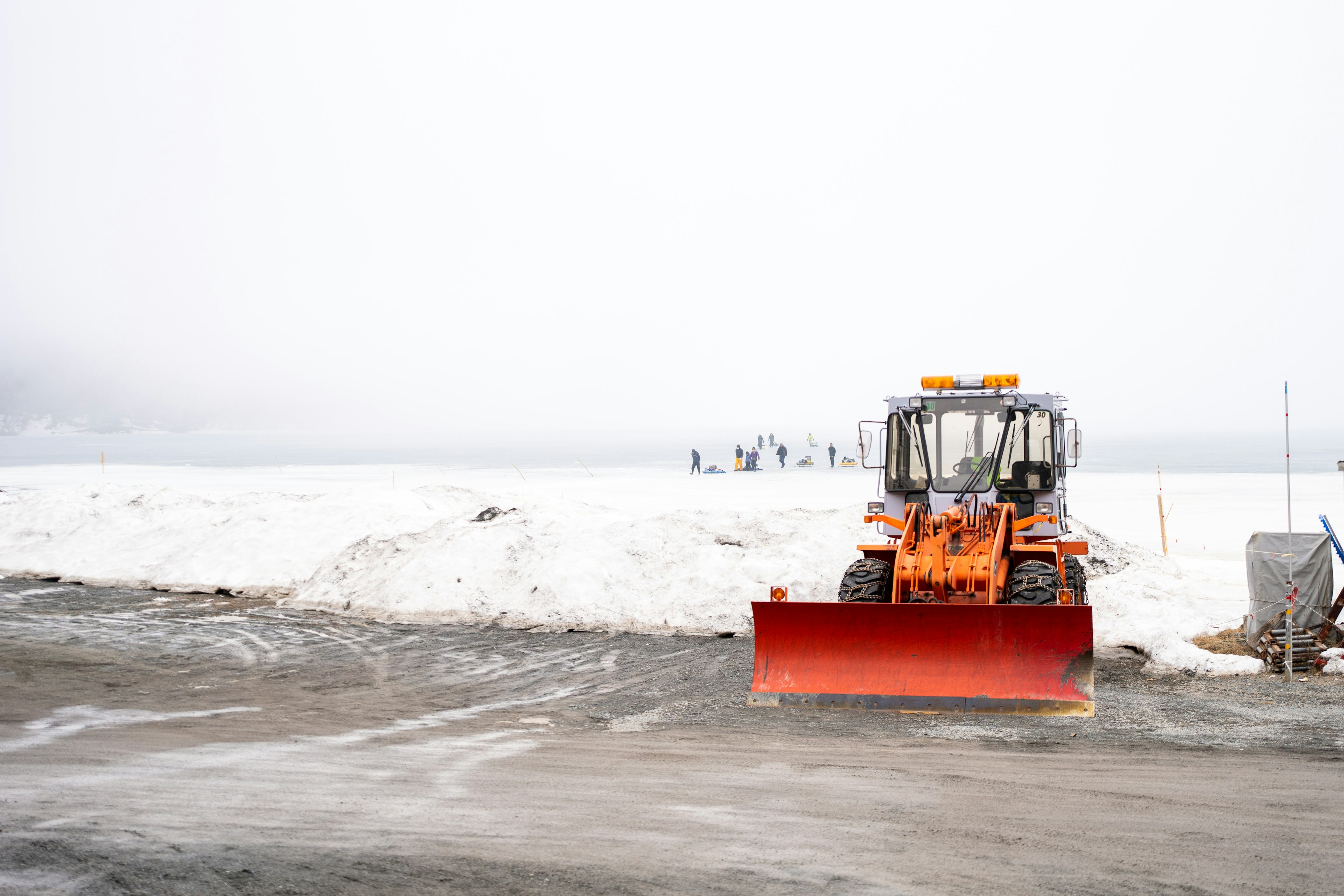 Chauffeur de déneigement orange nettoyant la neige blanche dans un paysage brumeux