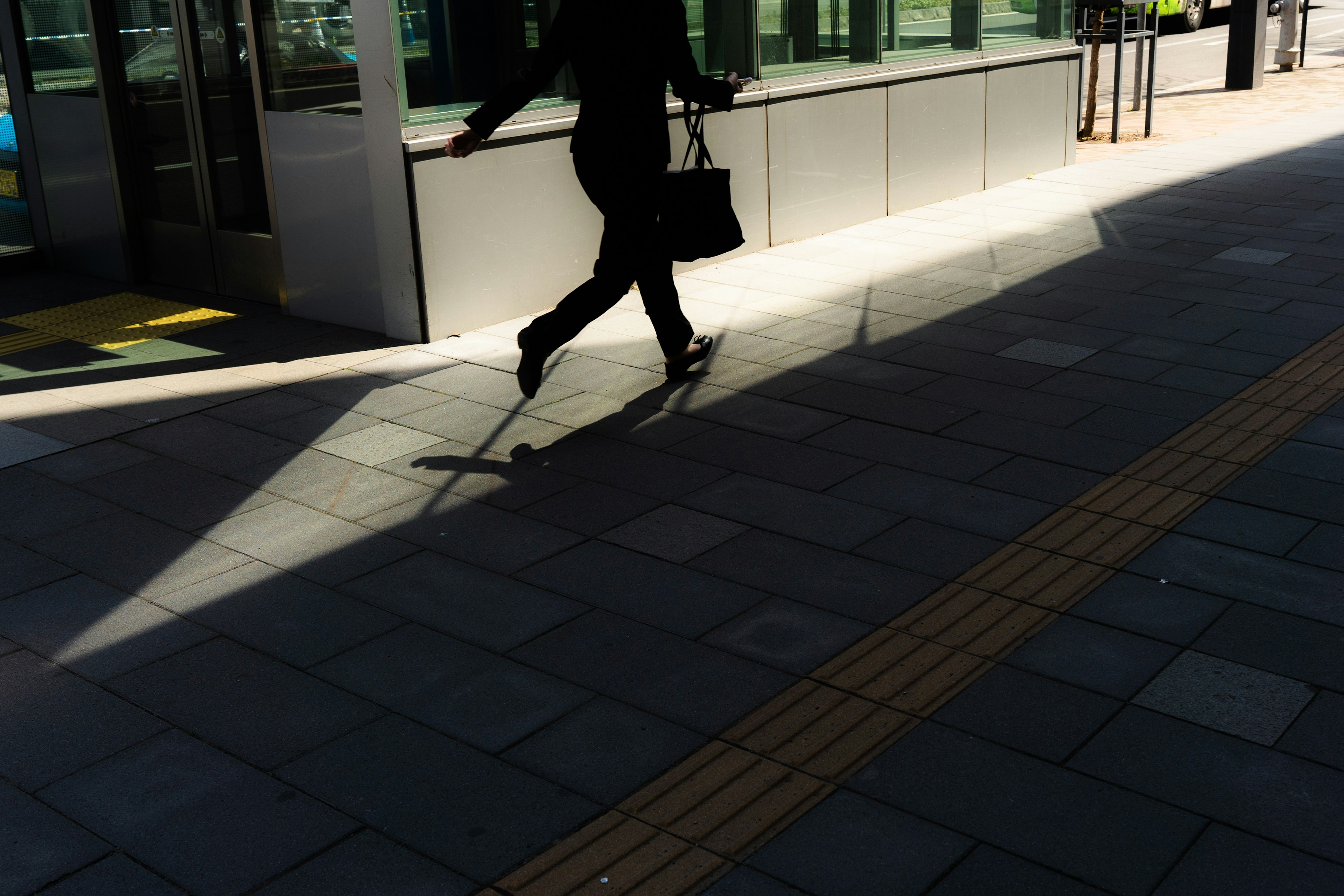 Schatten einer Person in Schwarz, die mit einer Tasche läuft Heller Licht- und Schattenkontrast