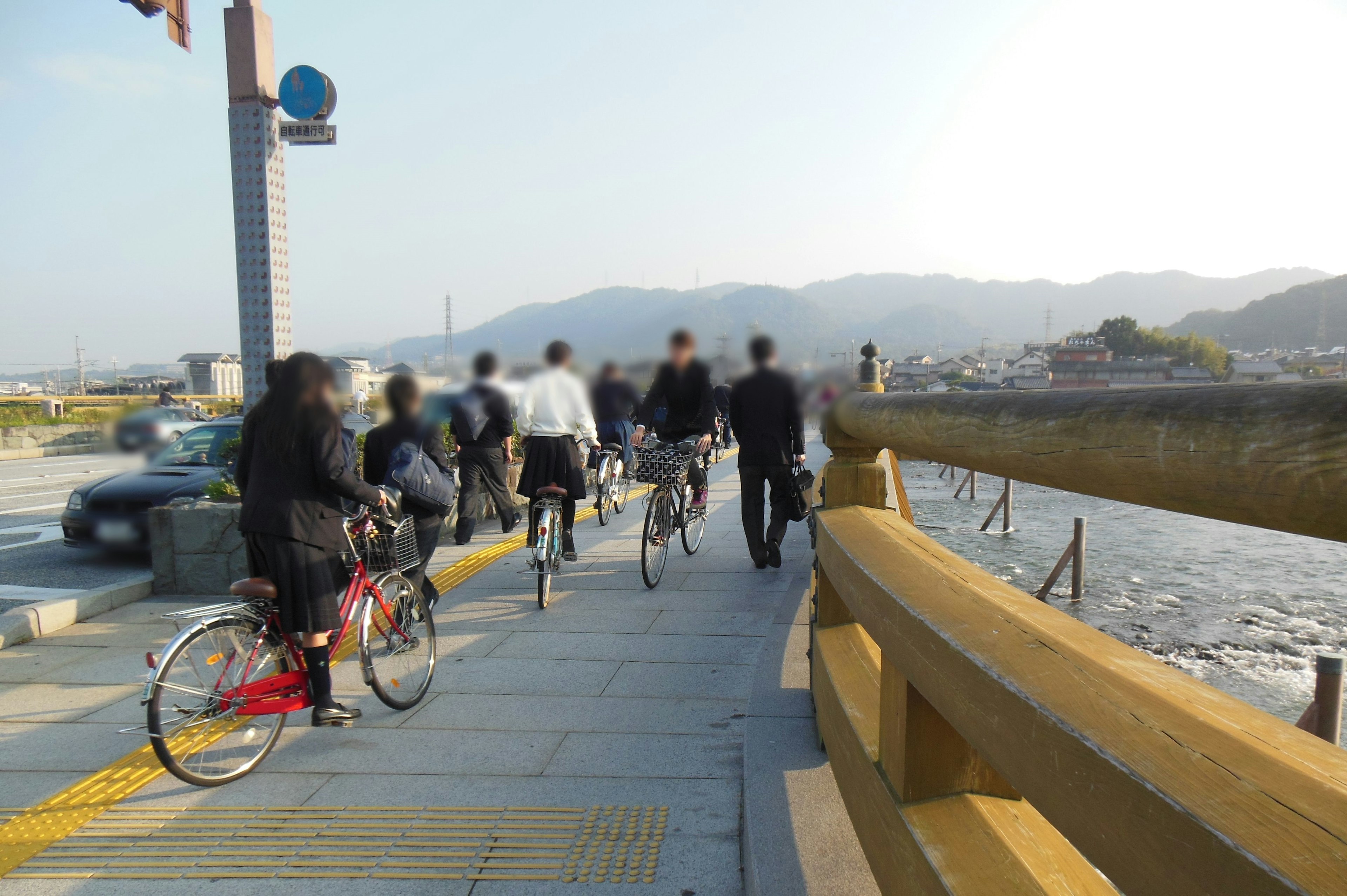 自転車に乗る人々が川沿いの歩道を走っている風景