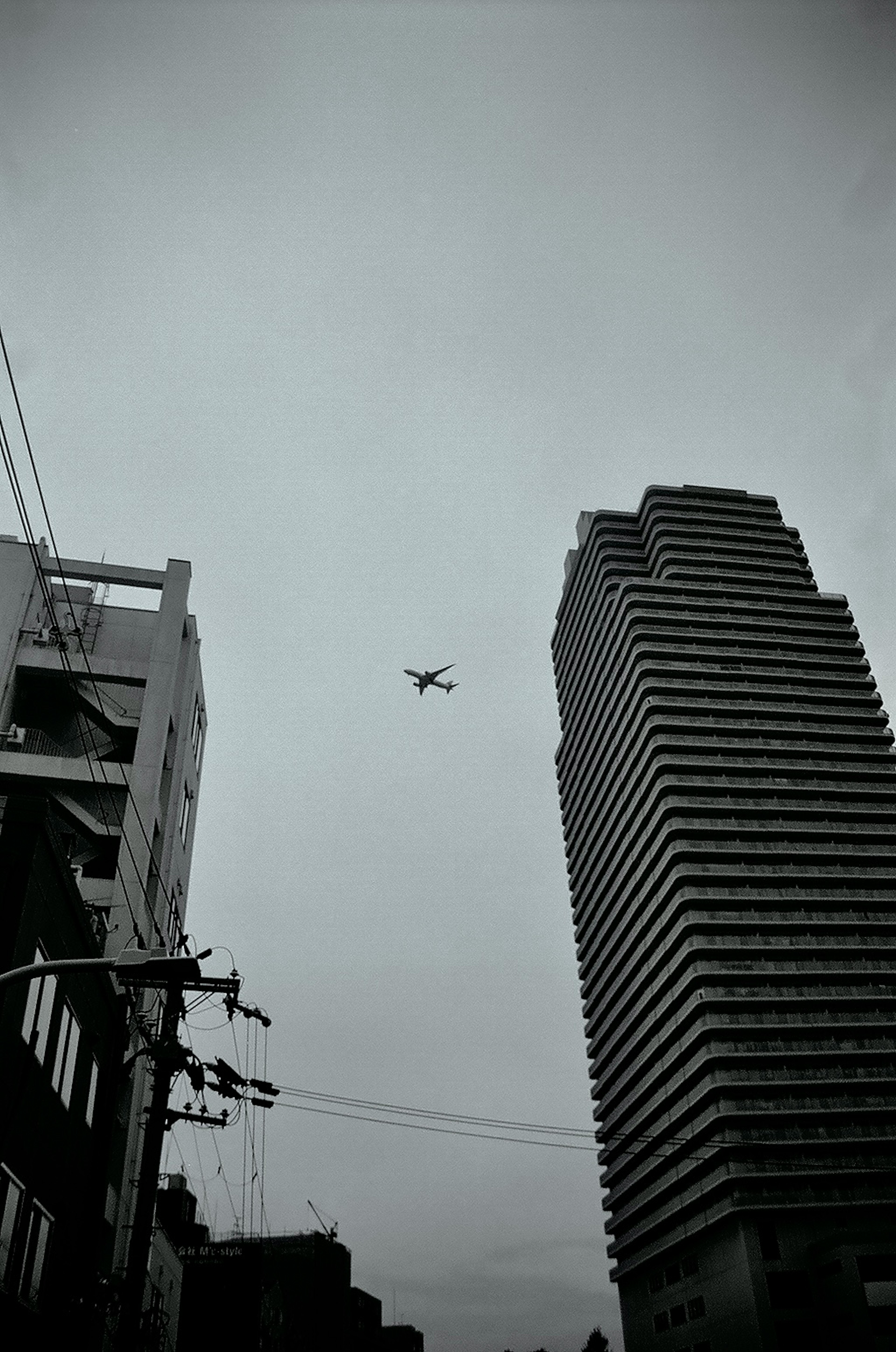 高層ビルの上空を飛ぶドローンと灰色の空