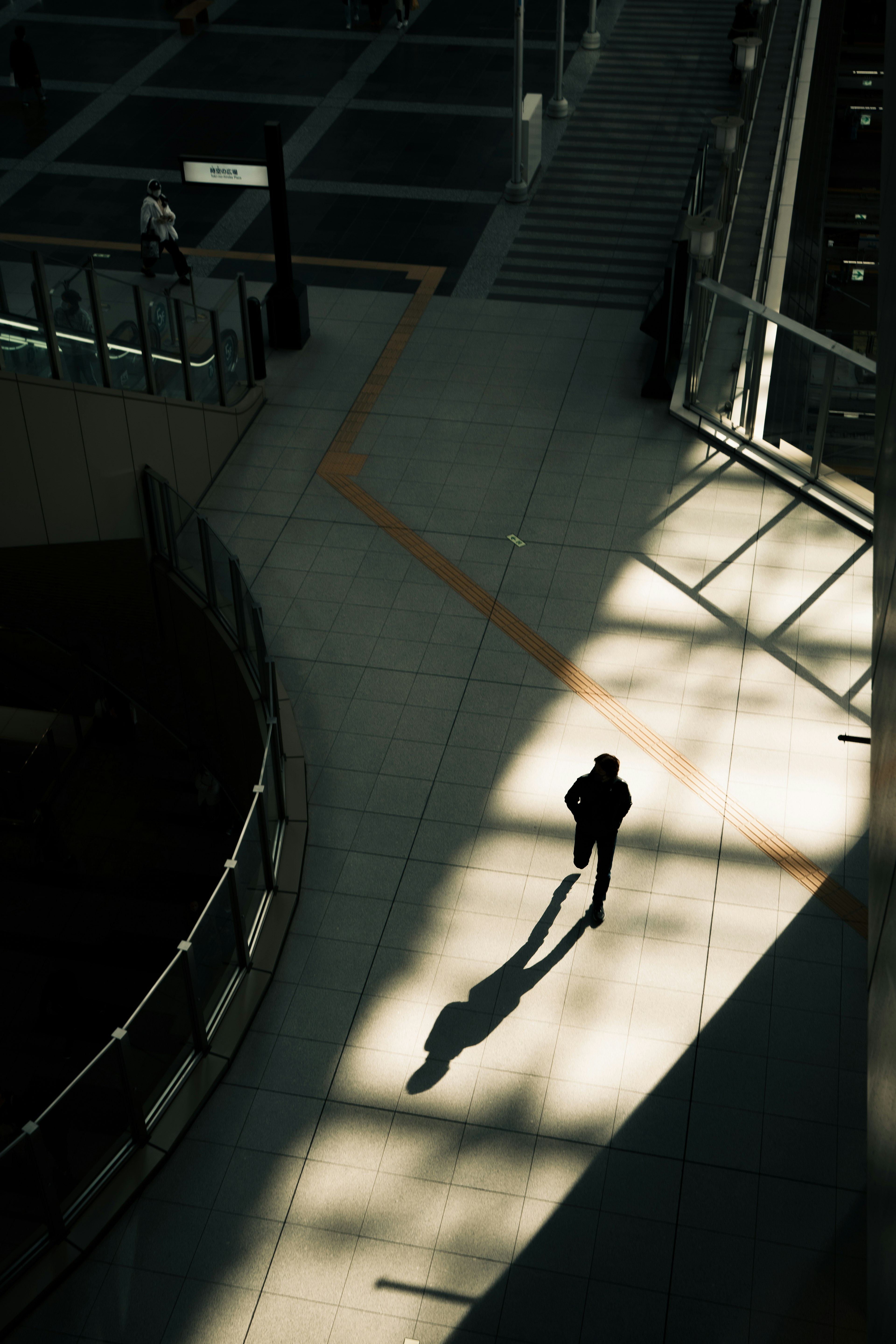 Silhouette of a person walking on a shadowed walkway