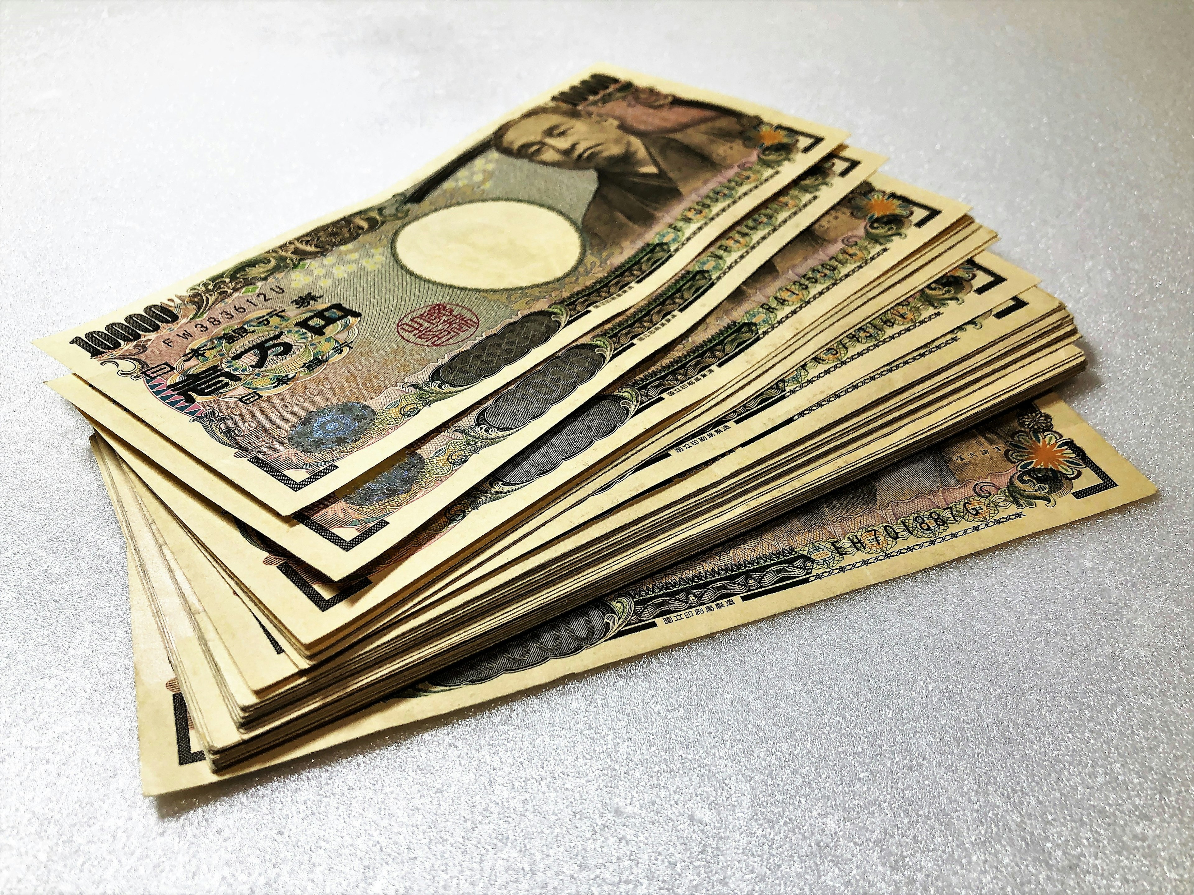 Stapel von japanischen Yen-Banknoten auf einem silbernen Hintergrund