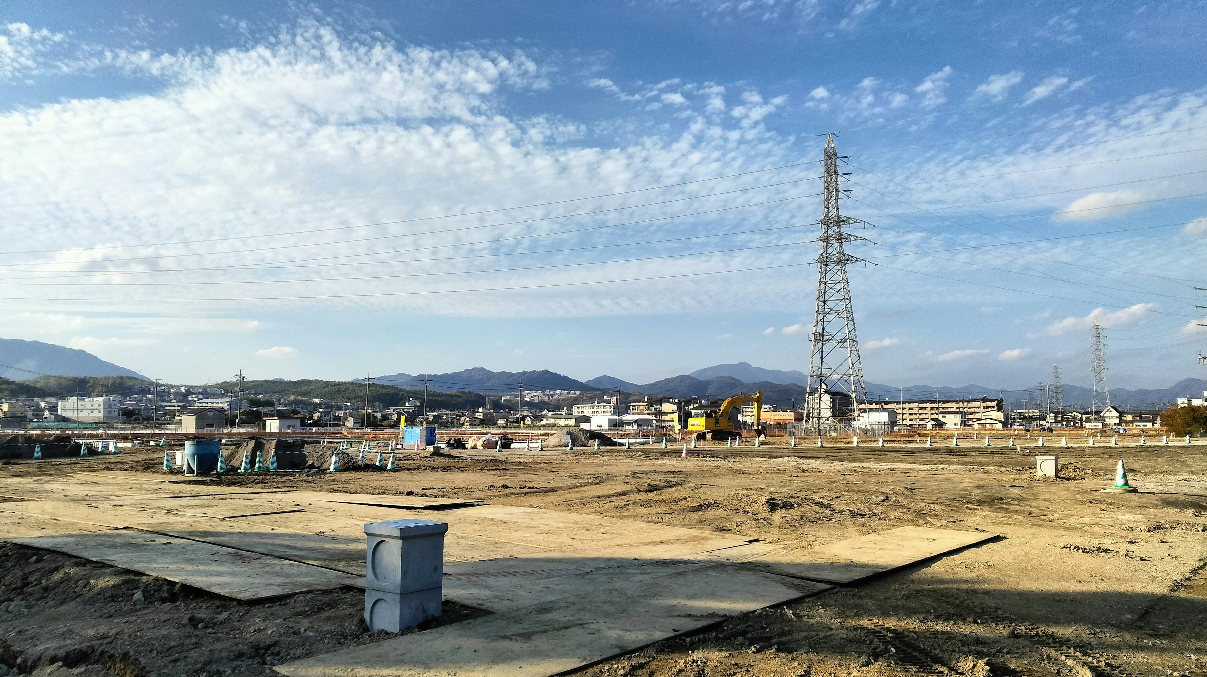 Weitläufiger Himmel und Baustelle mit Stromleitungen im Hintergrund