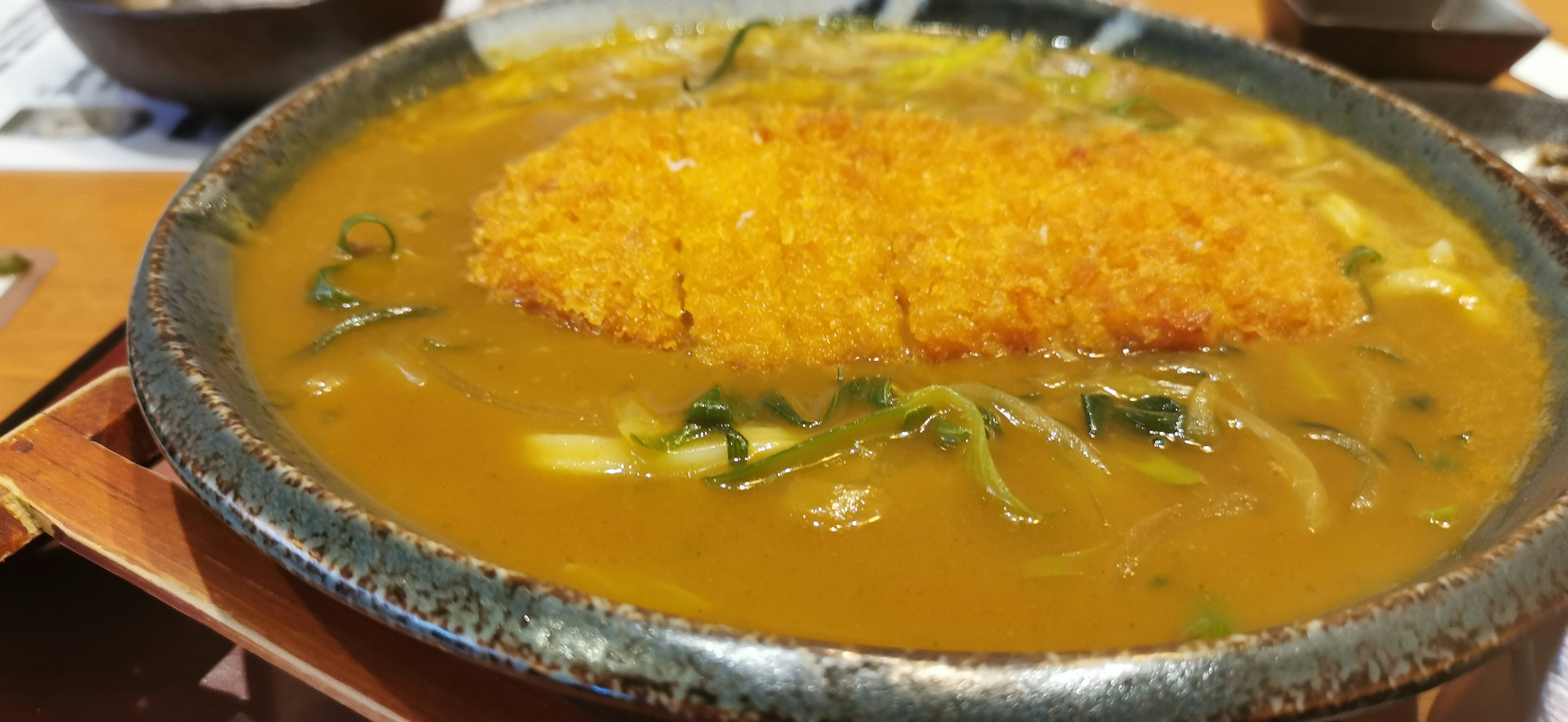 A bowl of curry udon topped with crispy tonkatsu