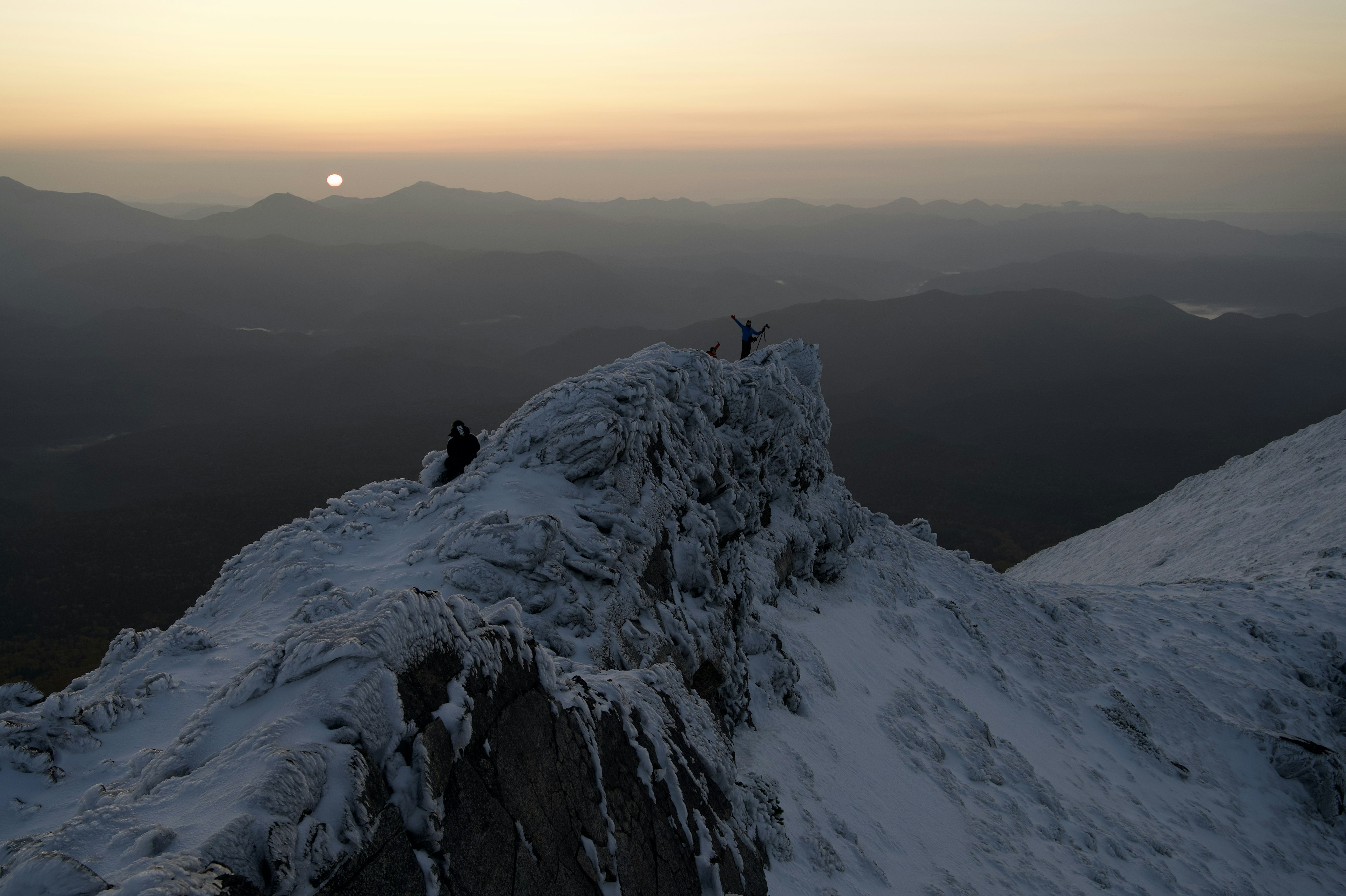 雪に覆われた山の頂上で登山者が活動している風景