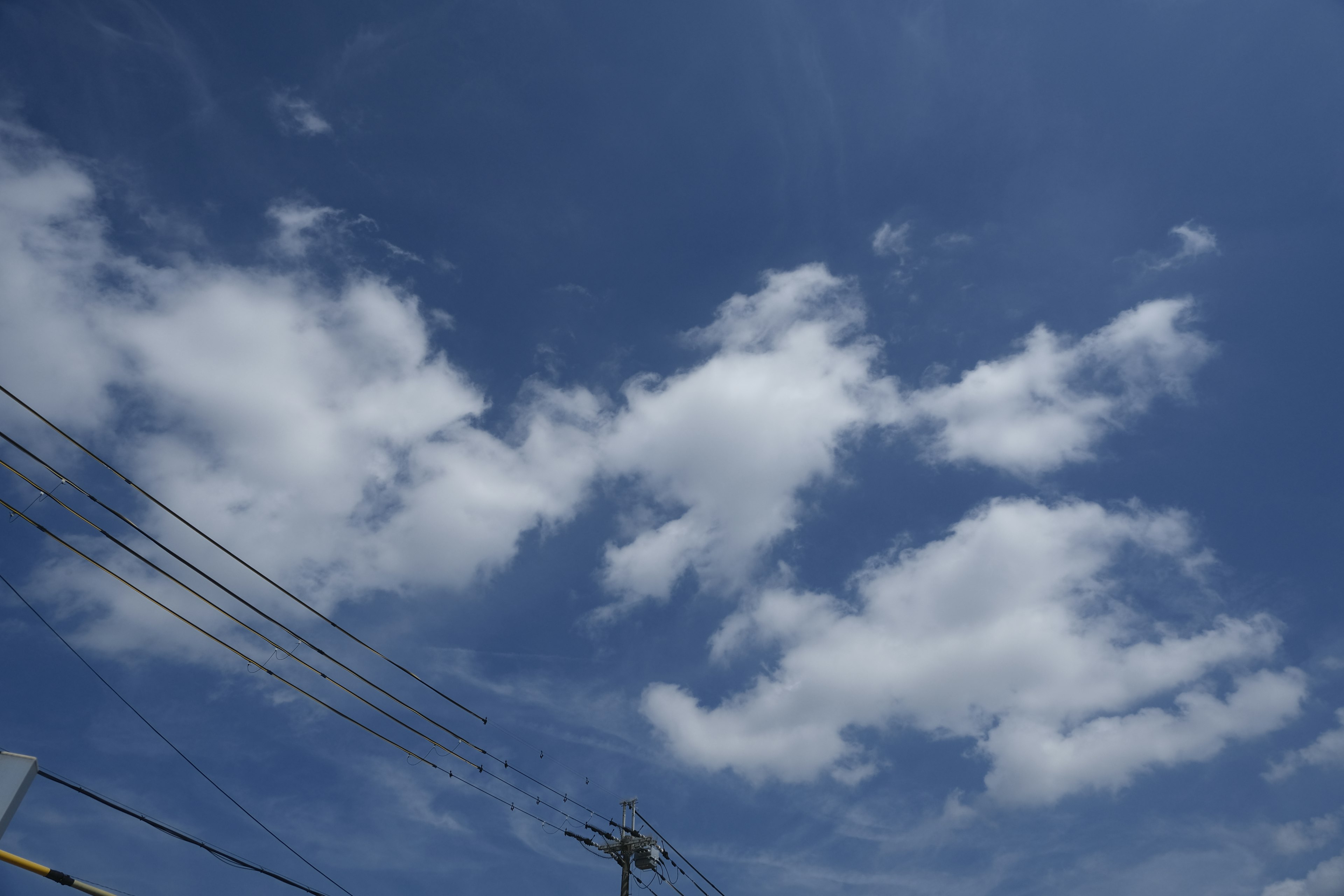 Nuvole bianche che fluttuano in un cielo blu con linee elettriche