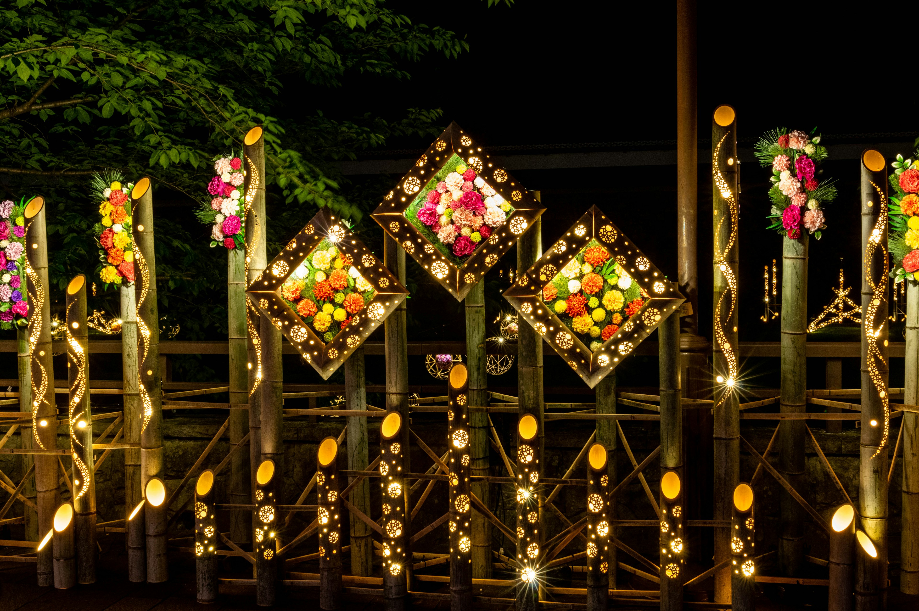 A beautifully decorated fence with colorful flowers and lights at night