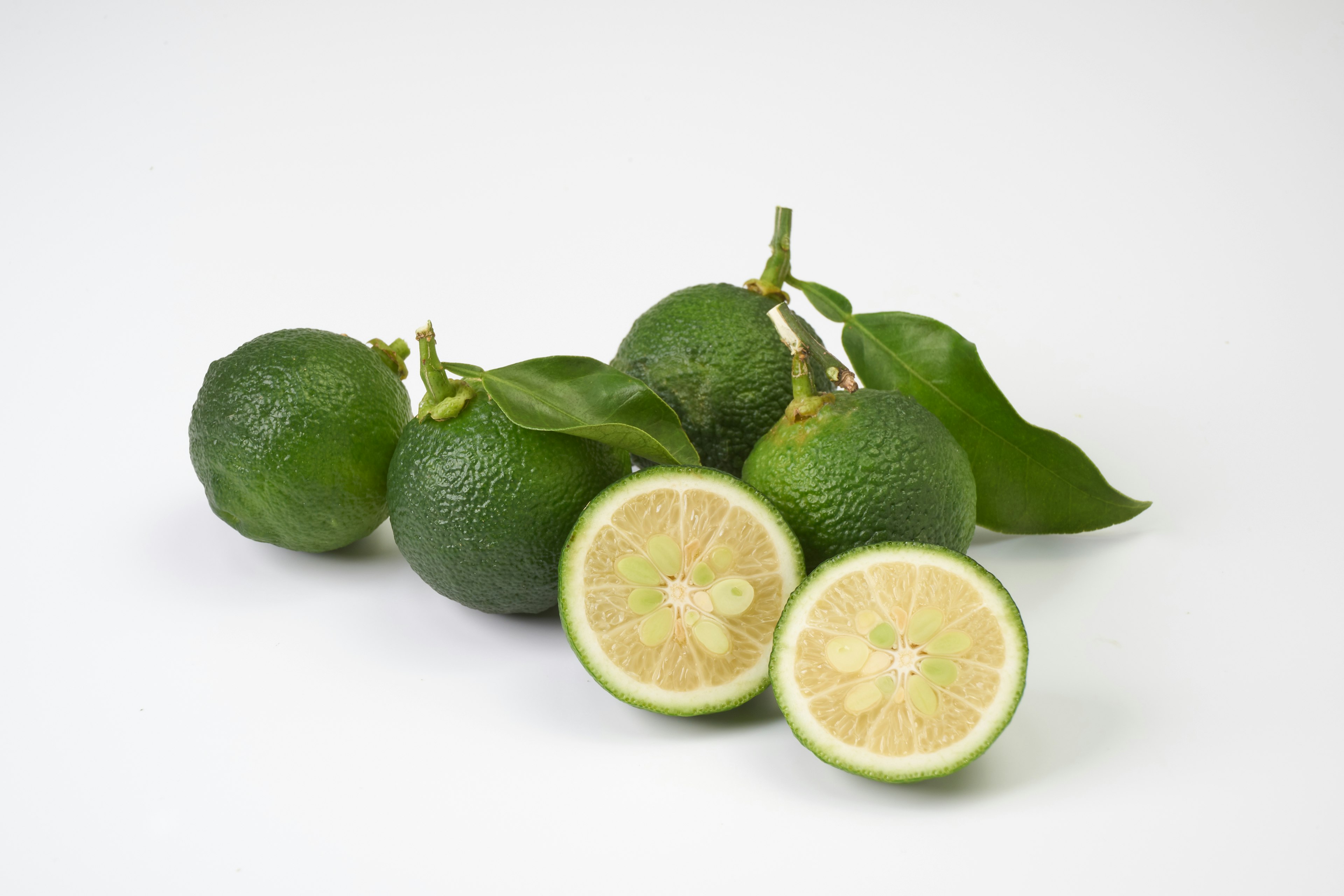 Fresh green limes with sliced halves displaying juicy interior