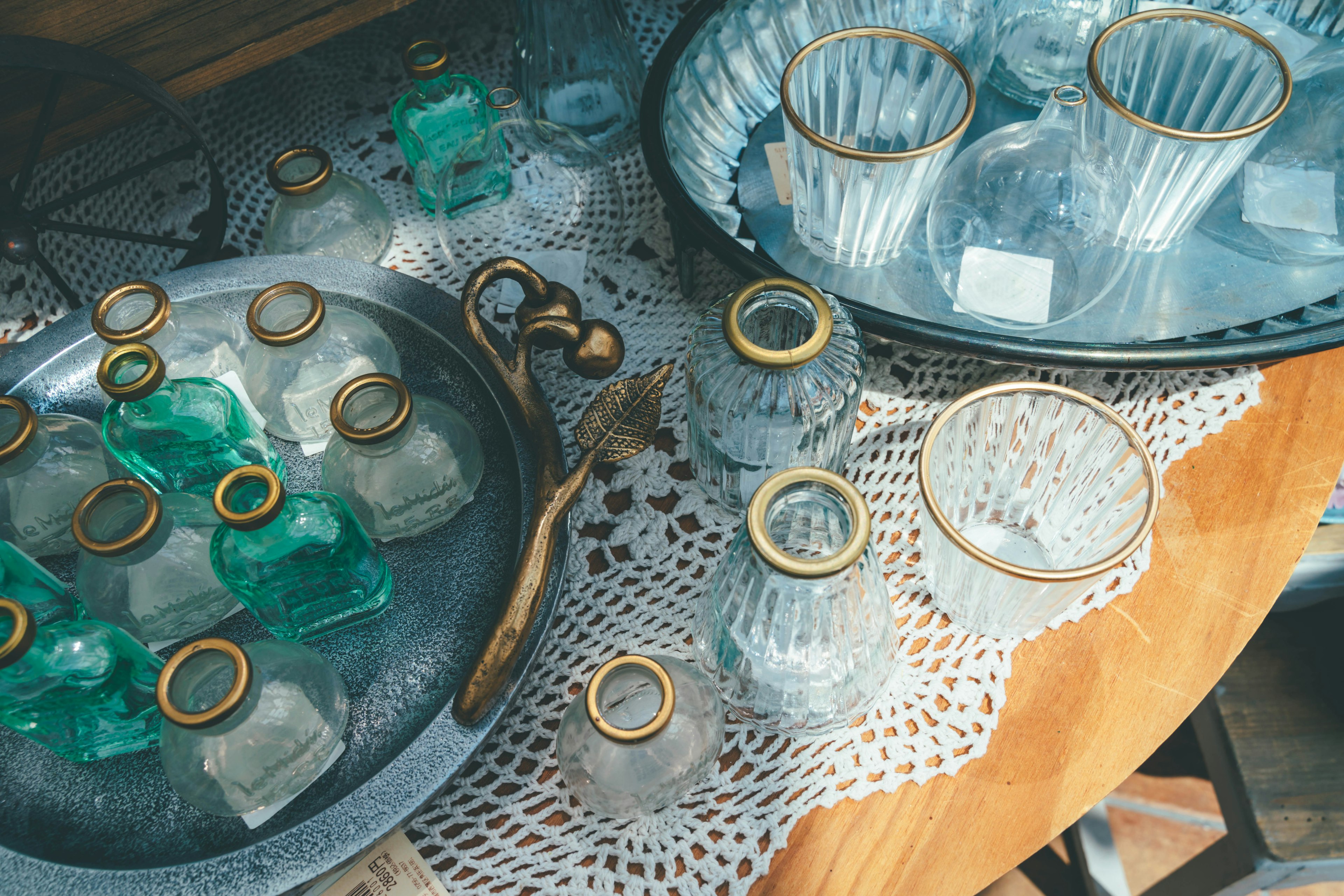 Green glass bottles and clear glass containers arranged on a table