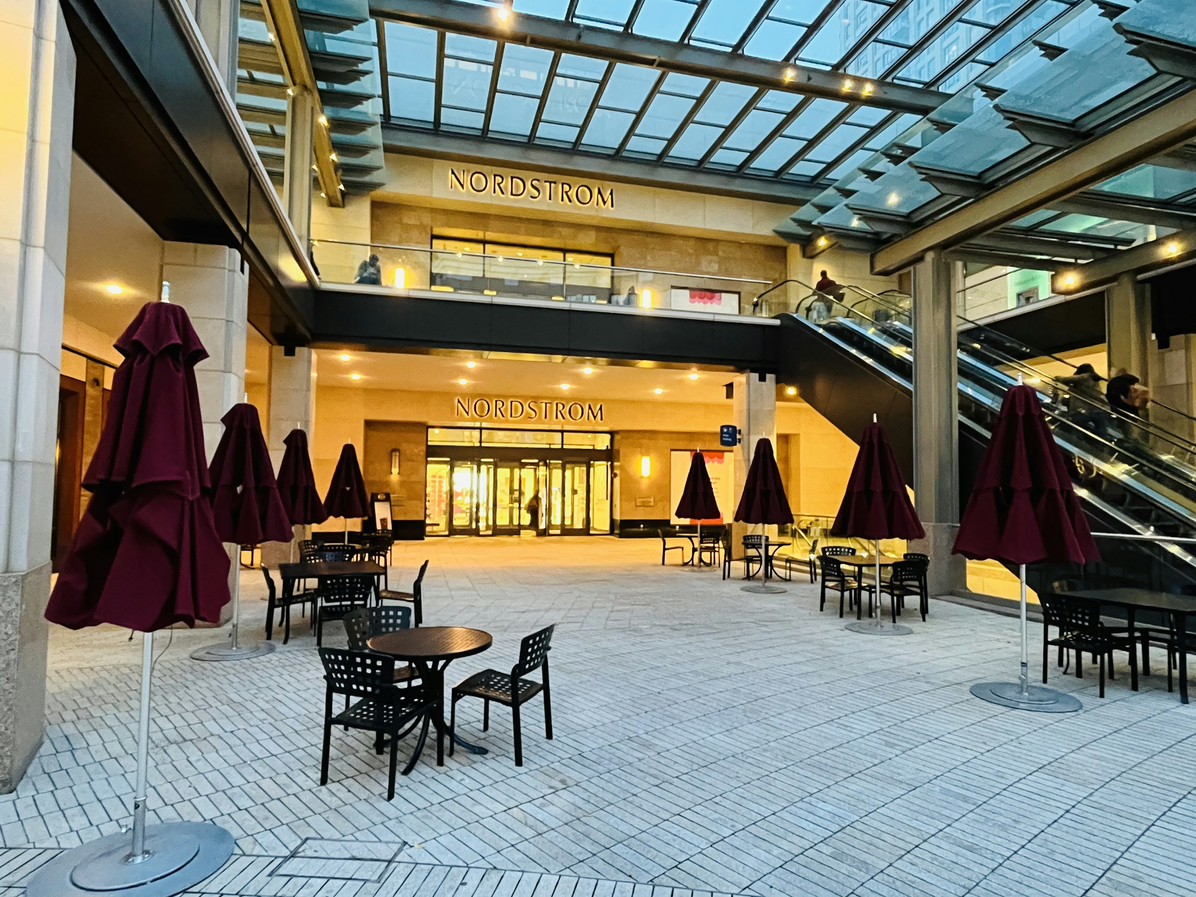 Indoor plaza with tables and chairs featuring red umbrellas