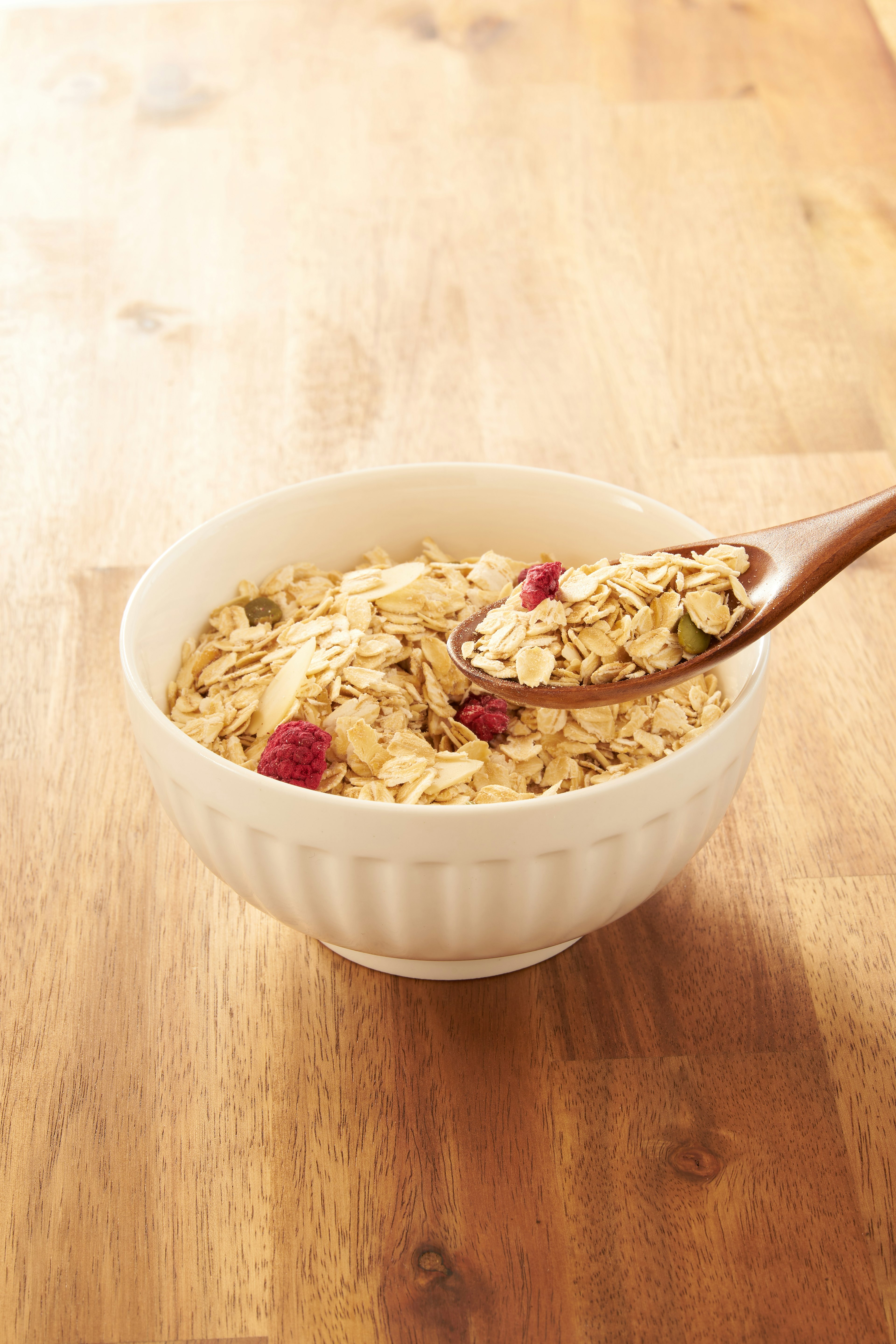 Bowl of oatmeal with raspberries and a wooden spoon