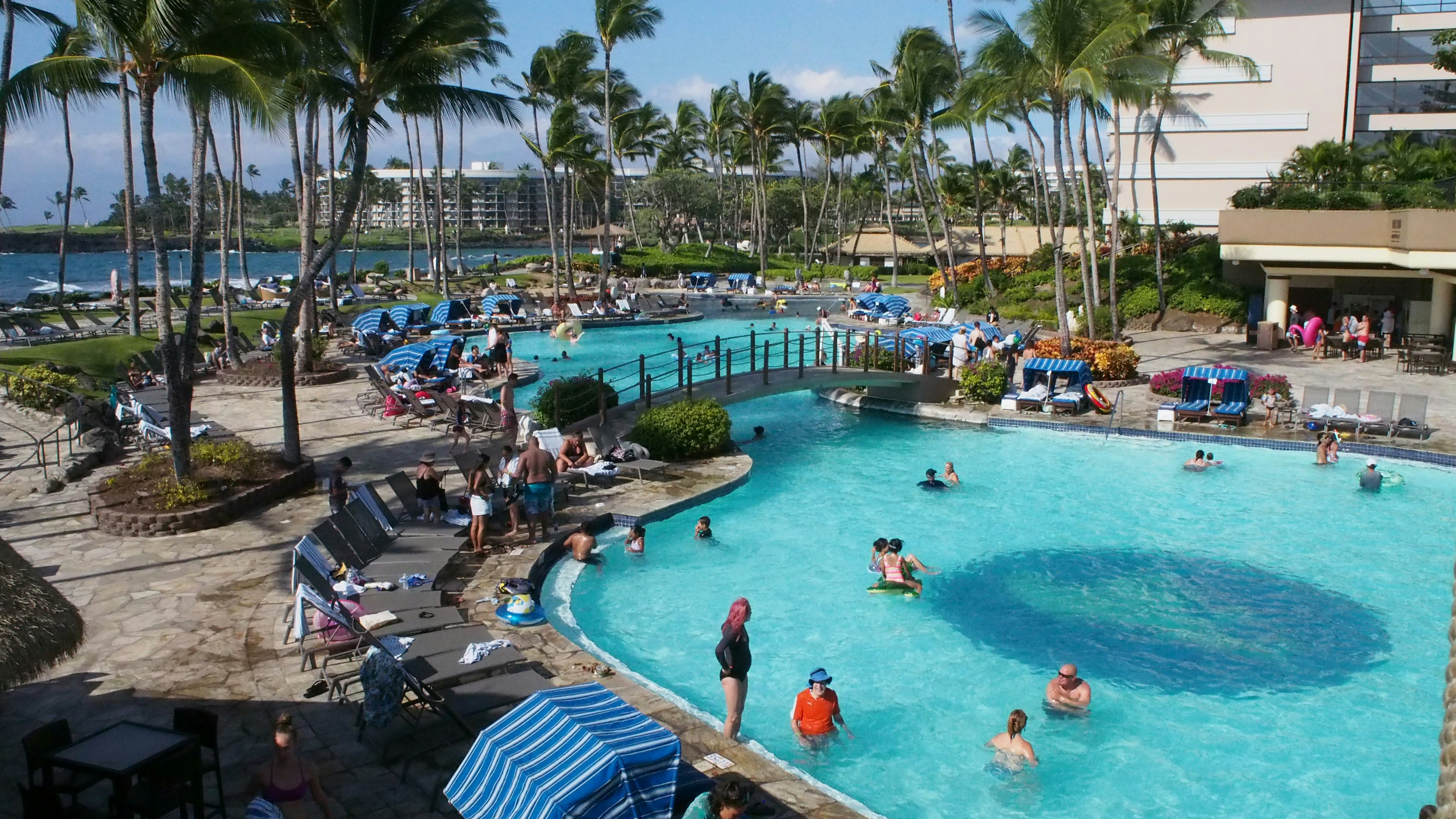 Piscina de resort con personas relajándose y agua azul clara