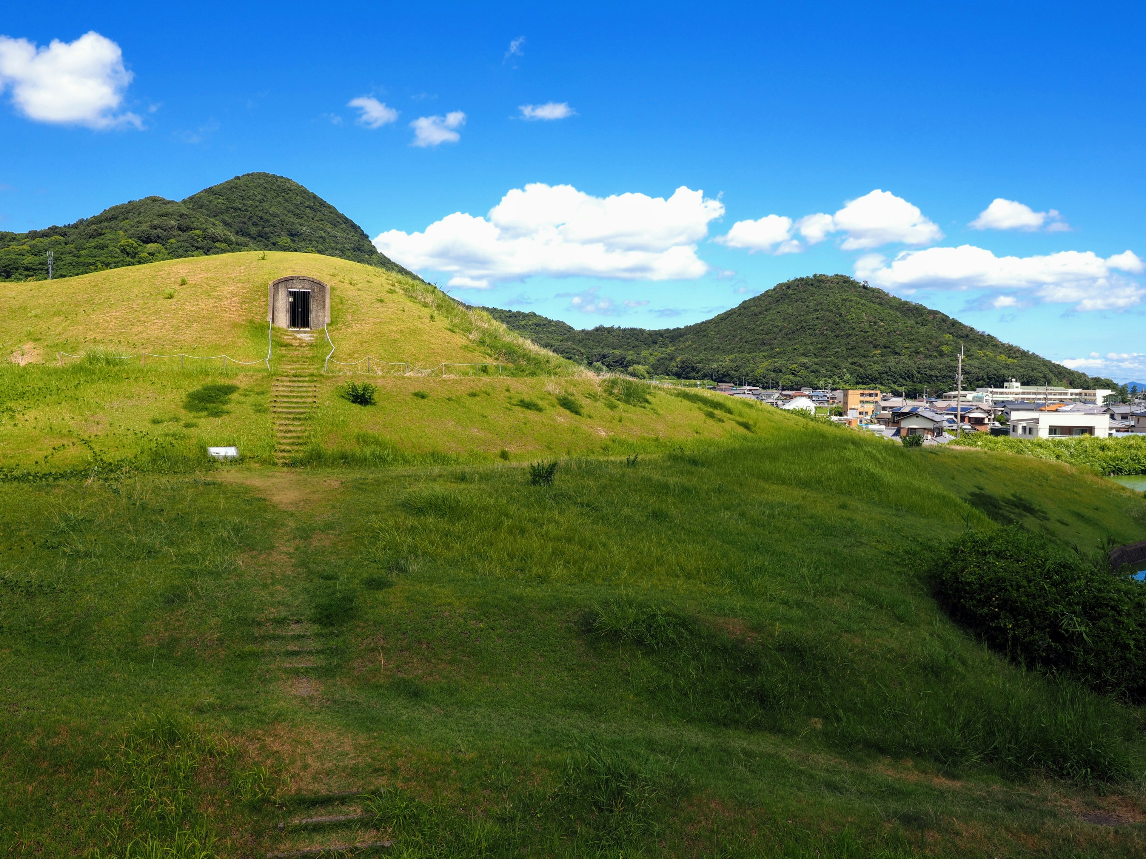 Collines verdoyantes sous un ciel bleu avec un petit bâtiment sur une colline