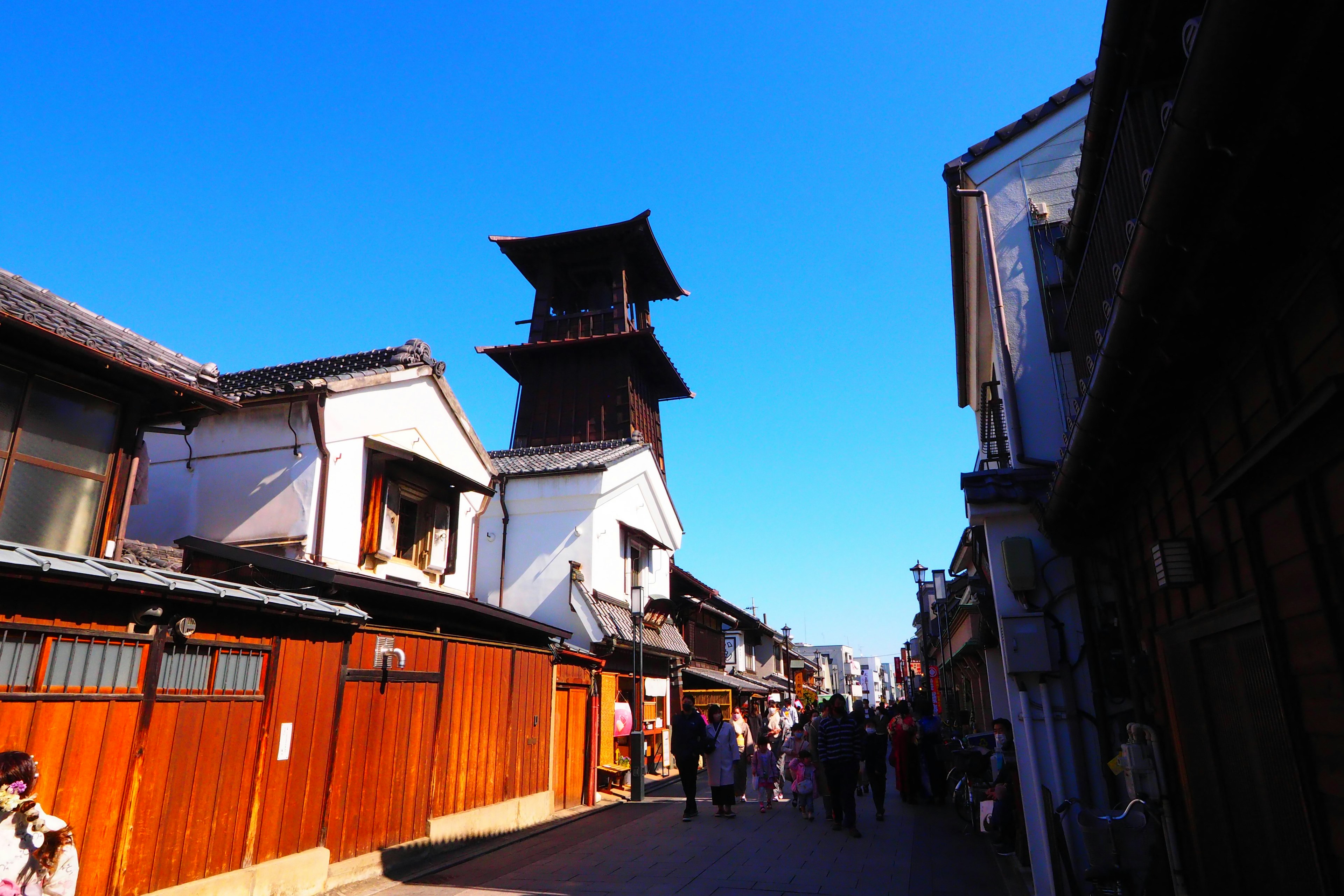 Traditionelle japanische Straßenszene mit einem Glockenturm unter einem klaren blauen Himmel