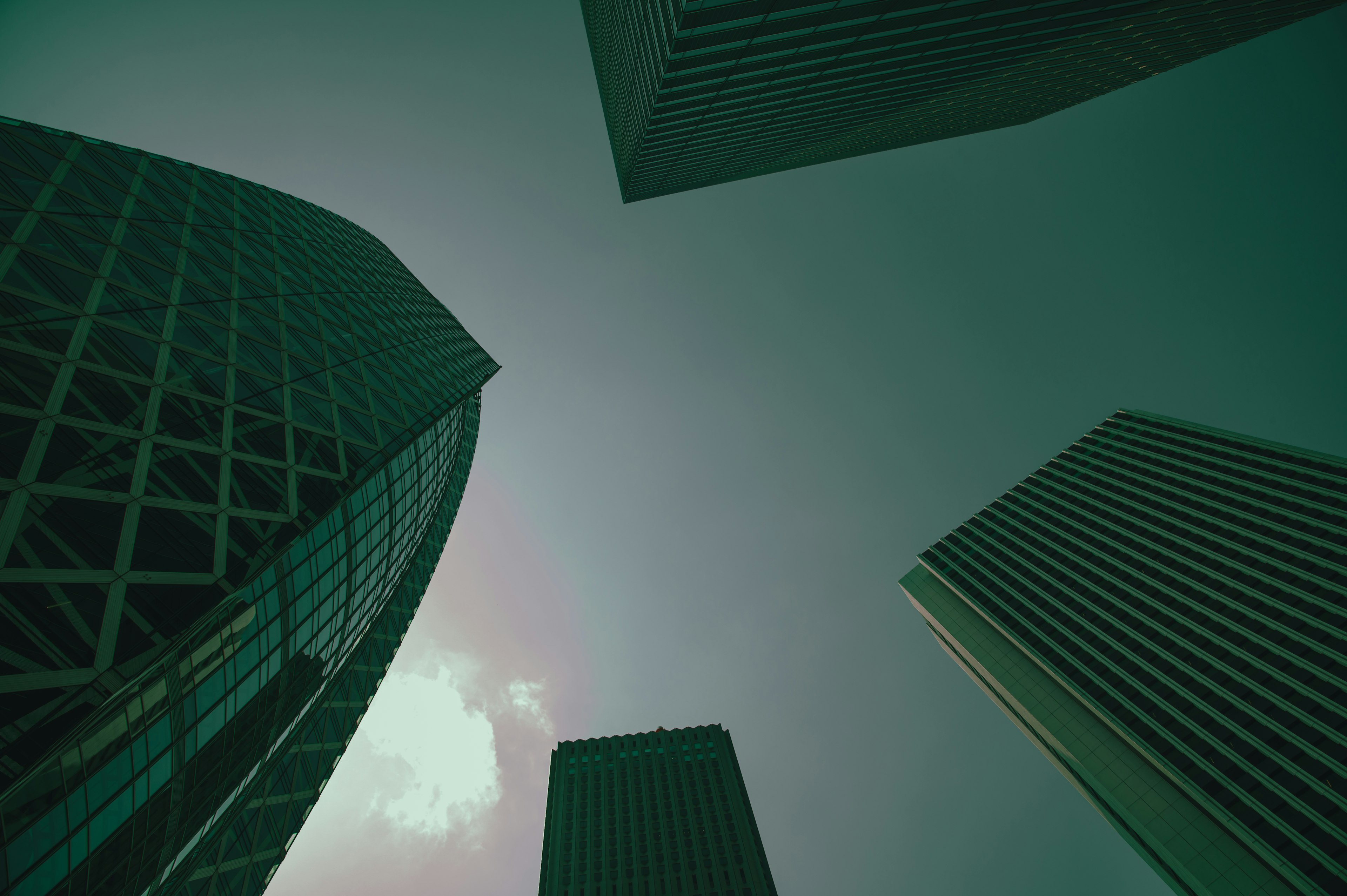 Urban landscape viewed from below tall buildings against a greenish sky