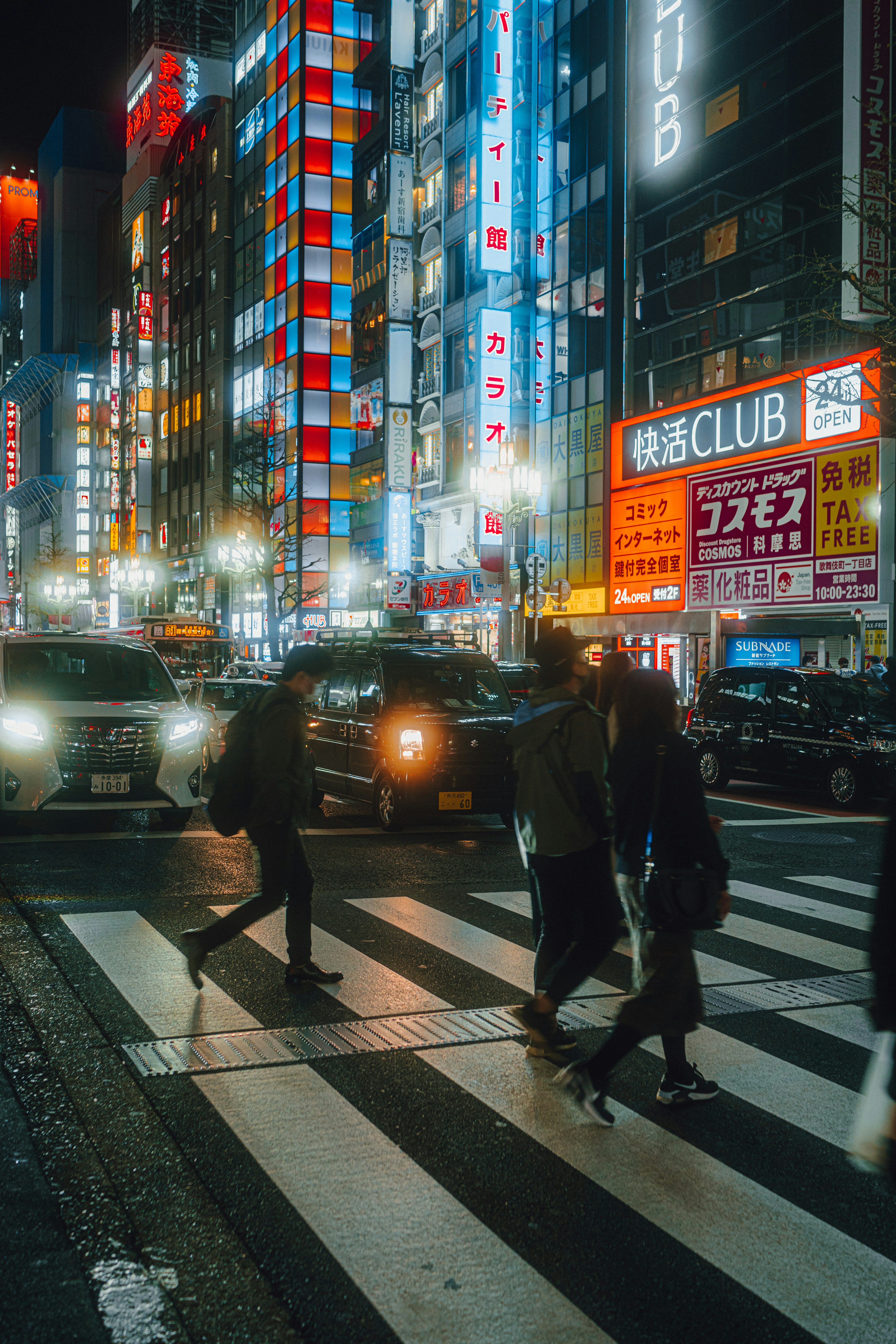 夜の東京の繁華街にあるカラフルなネオン看板と交差点を渡る人々