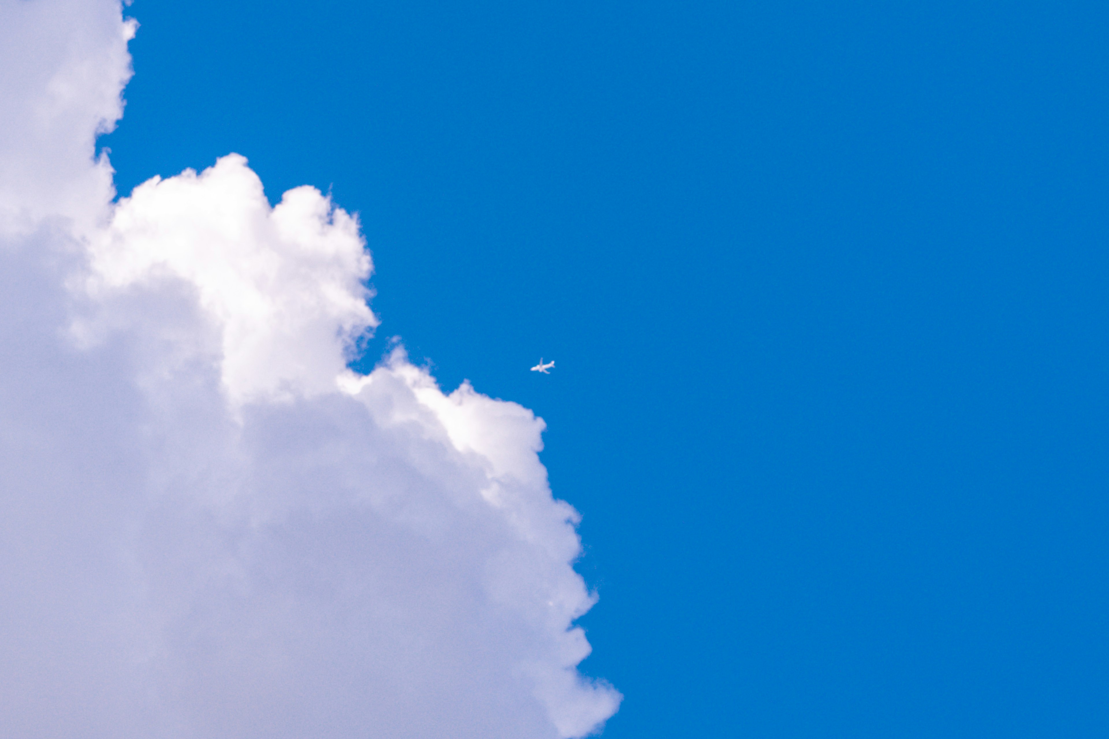 Ein kleines Flugzeug fliegt im klaren blauen Himmel mit fluffigen weißen Wolken