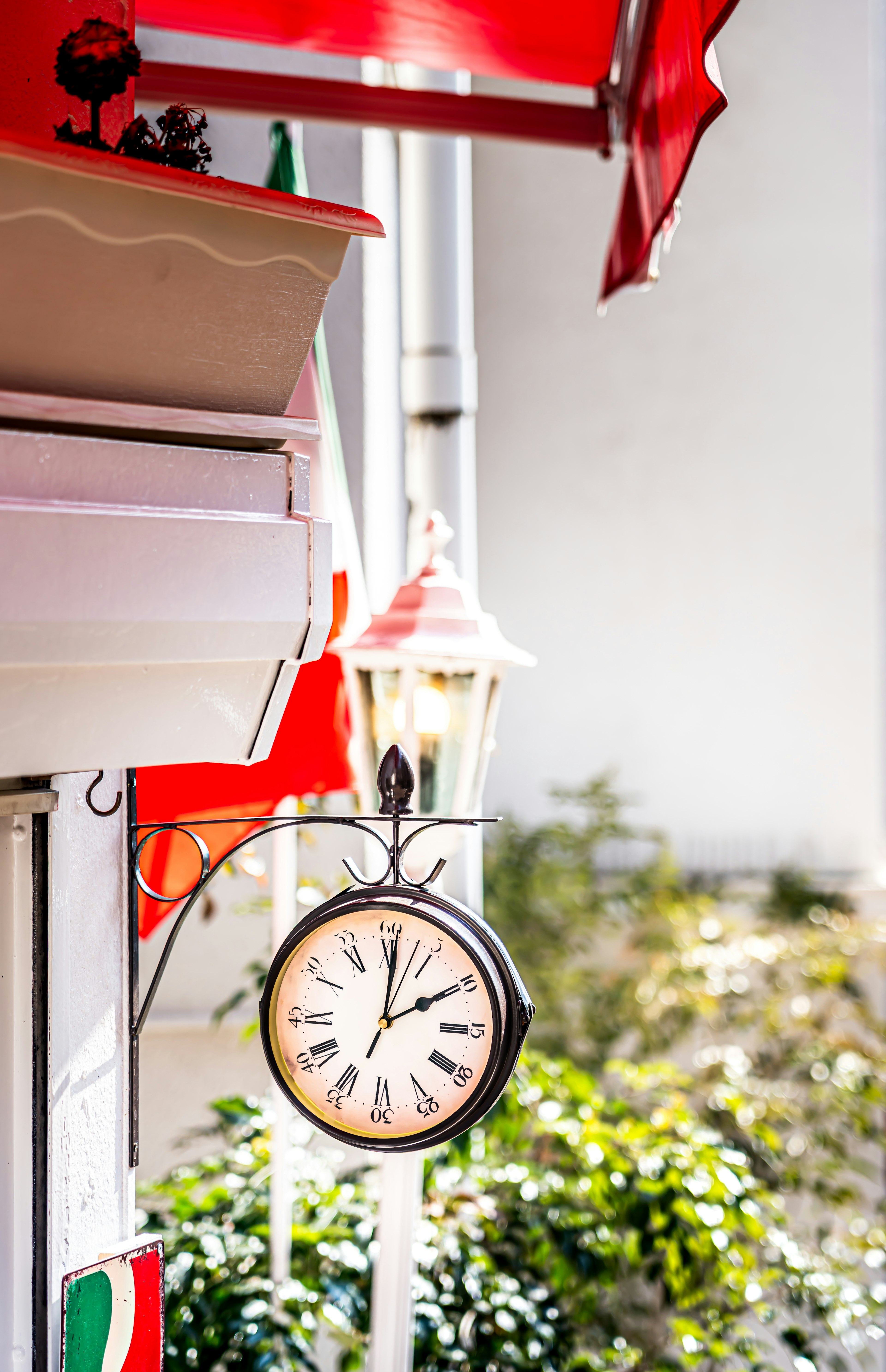 Clock hanging under a red umbrella with a lantern nearby