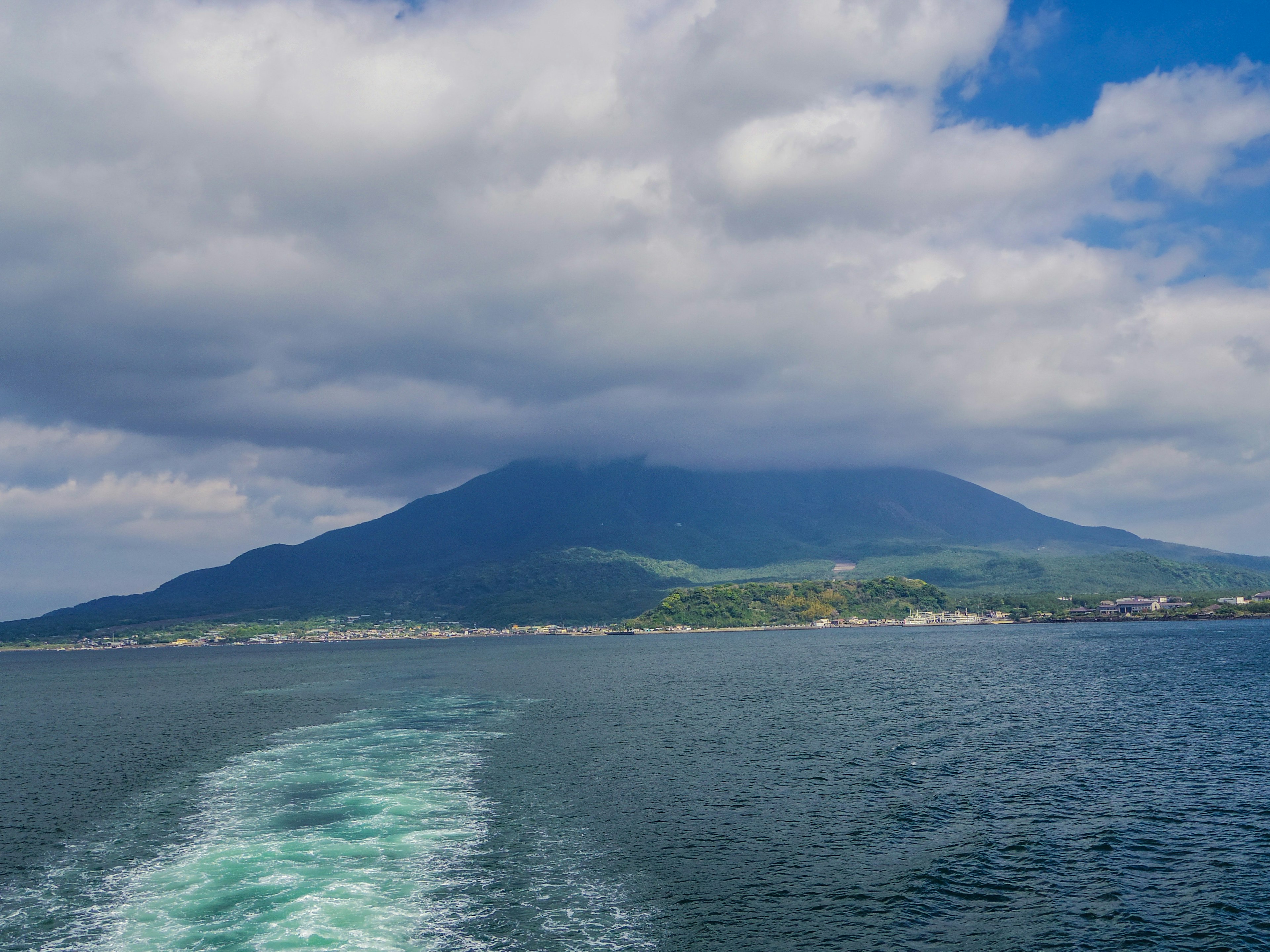 Scenic view of a mountain with clouds and blue sky over calm water