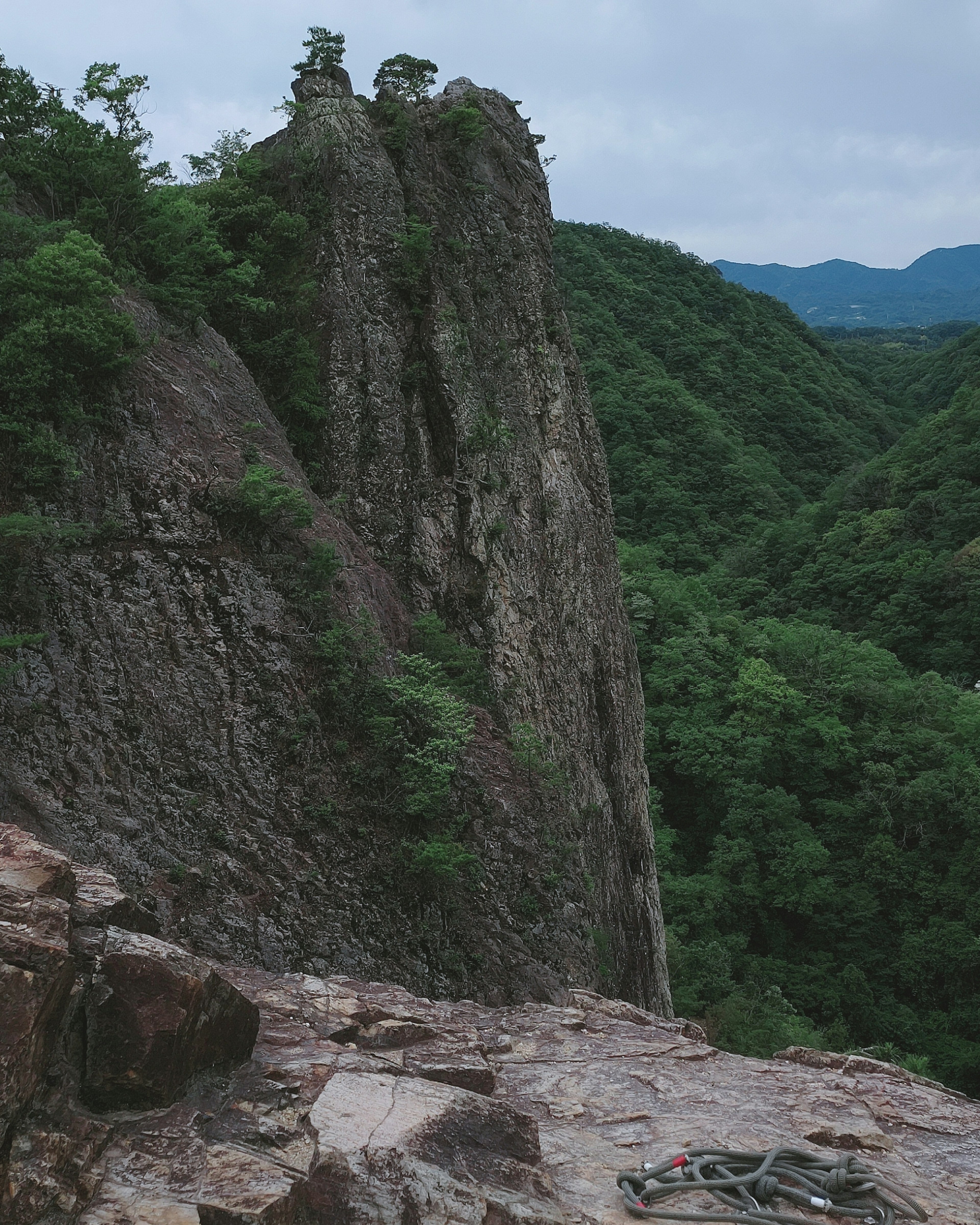 緑豊かな山々に囲まれた急な岩峰の風景