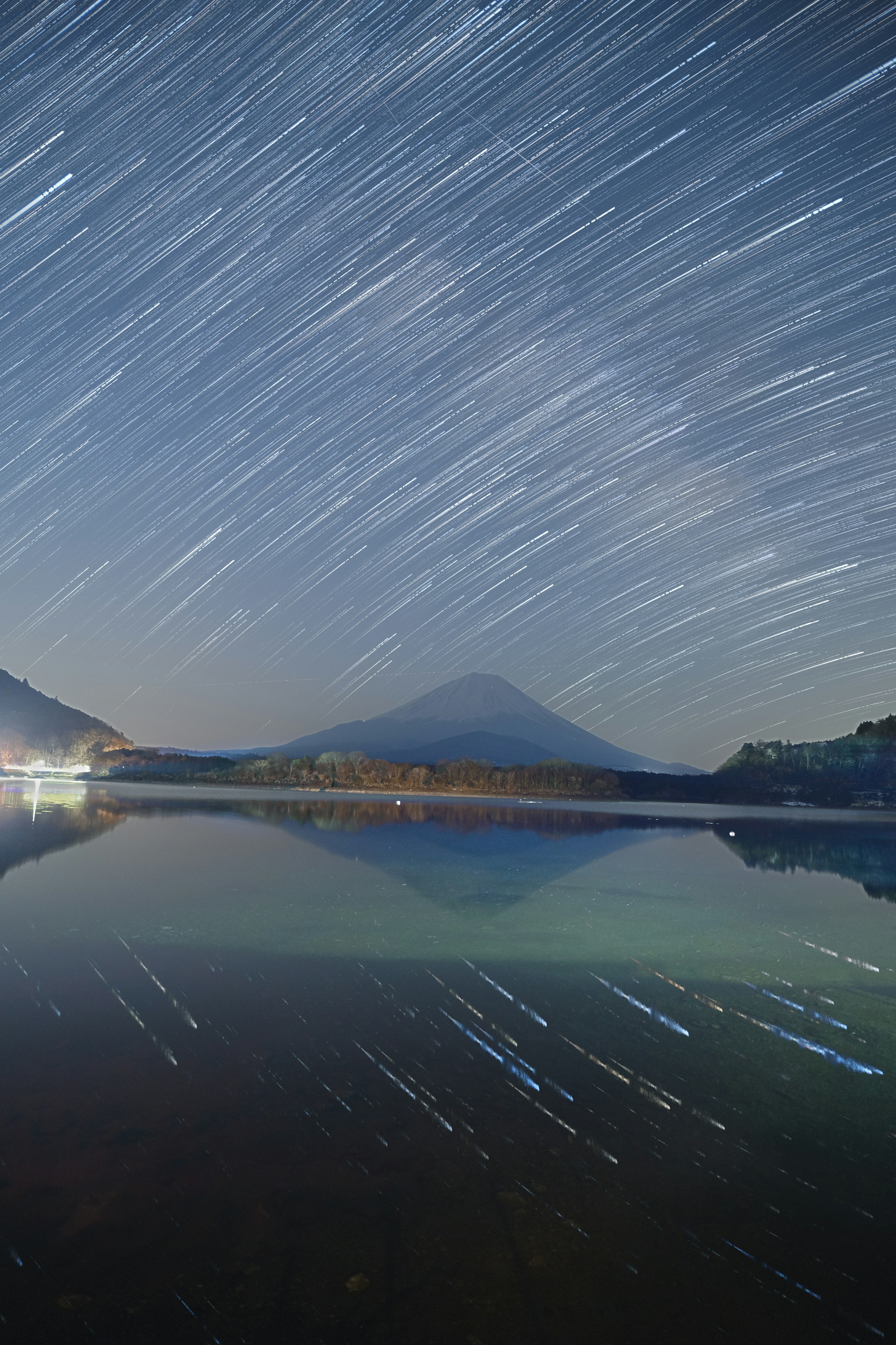 星の軌跡が映る湖と山の風景