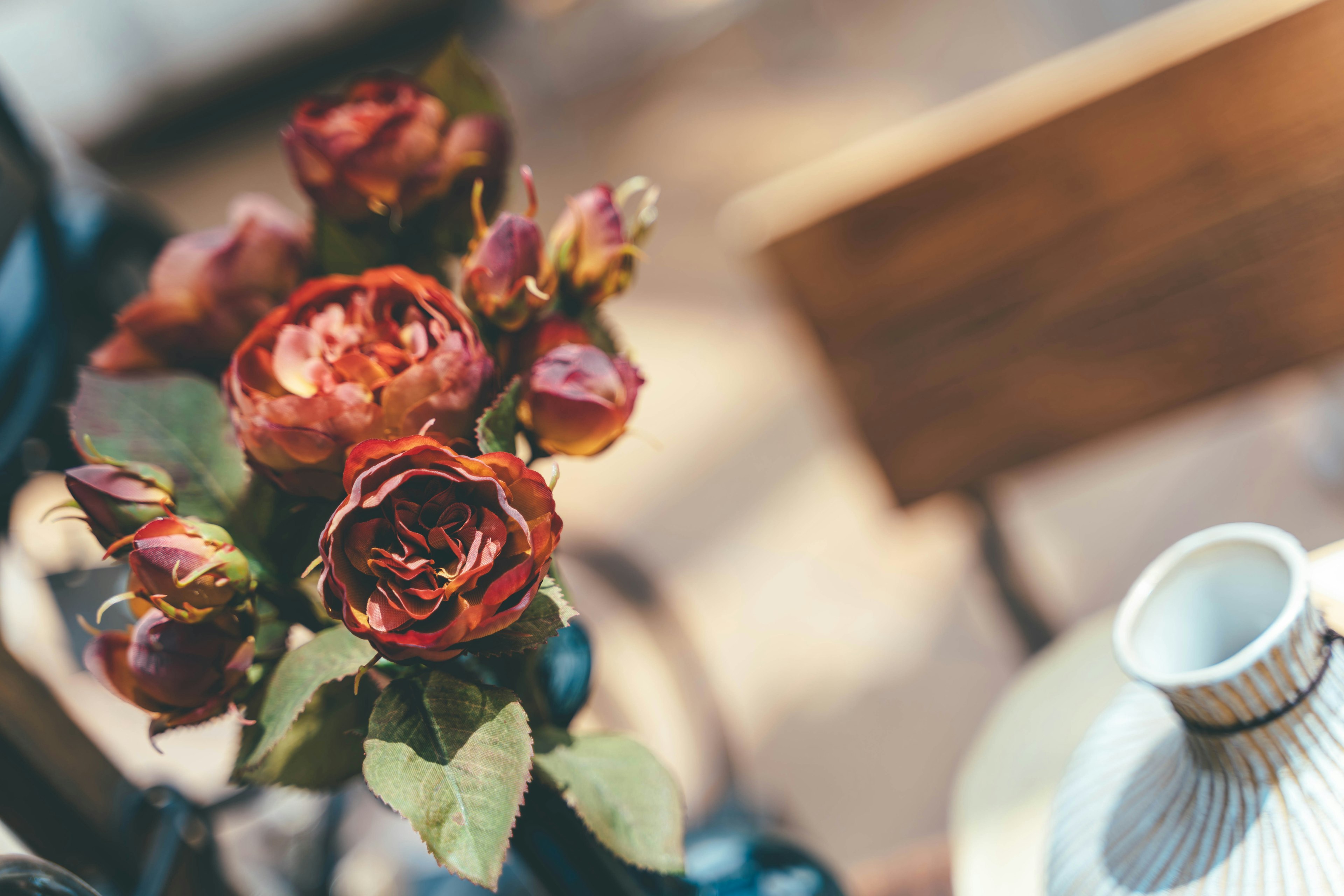 Ein Strauß roter Rosen und eine weiße Keramikvase auf einem Tisch