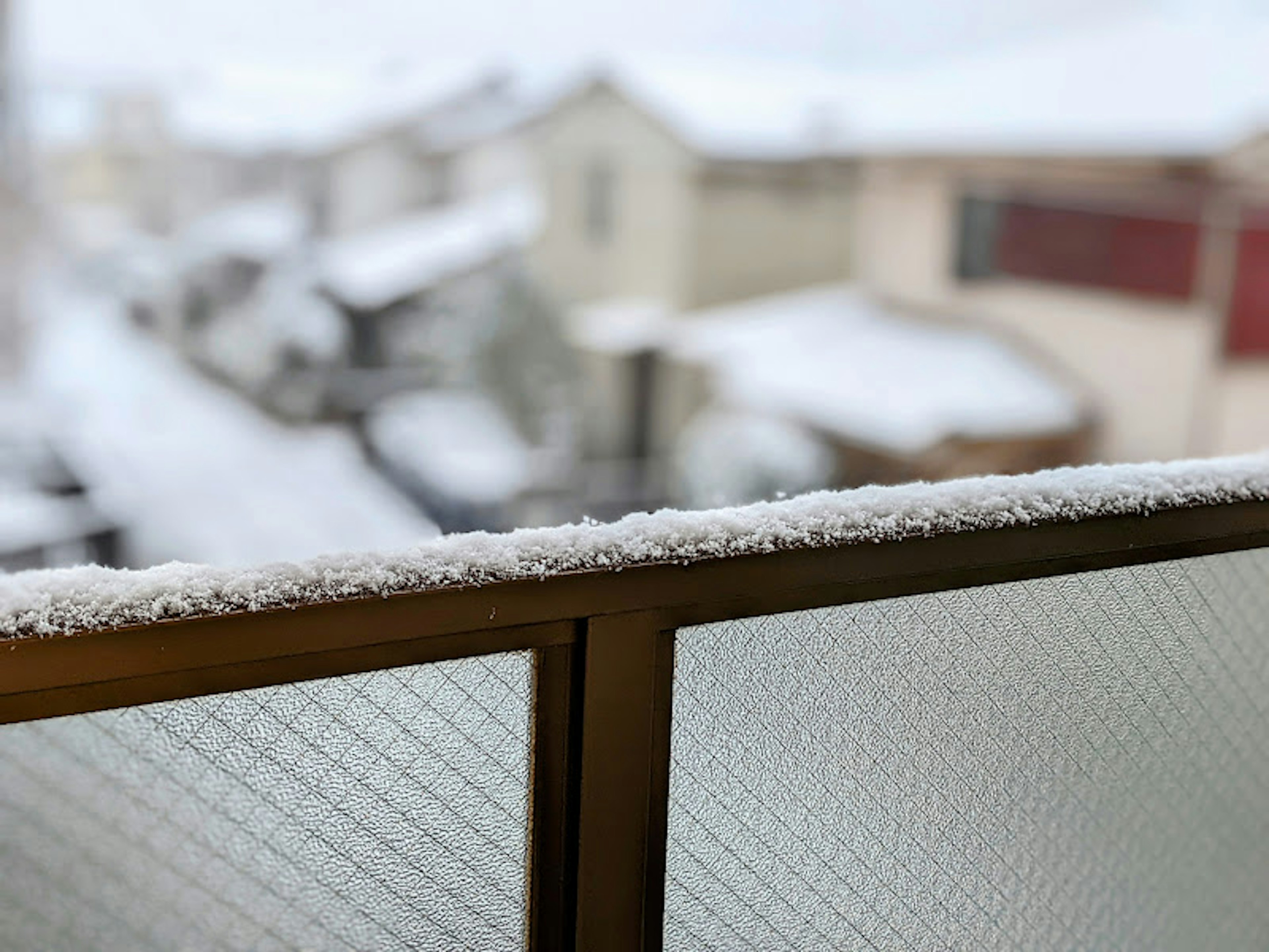 View from a balcony with snow covering the railing and rooftops