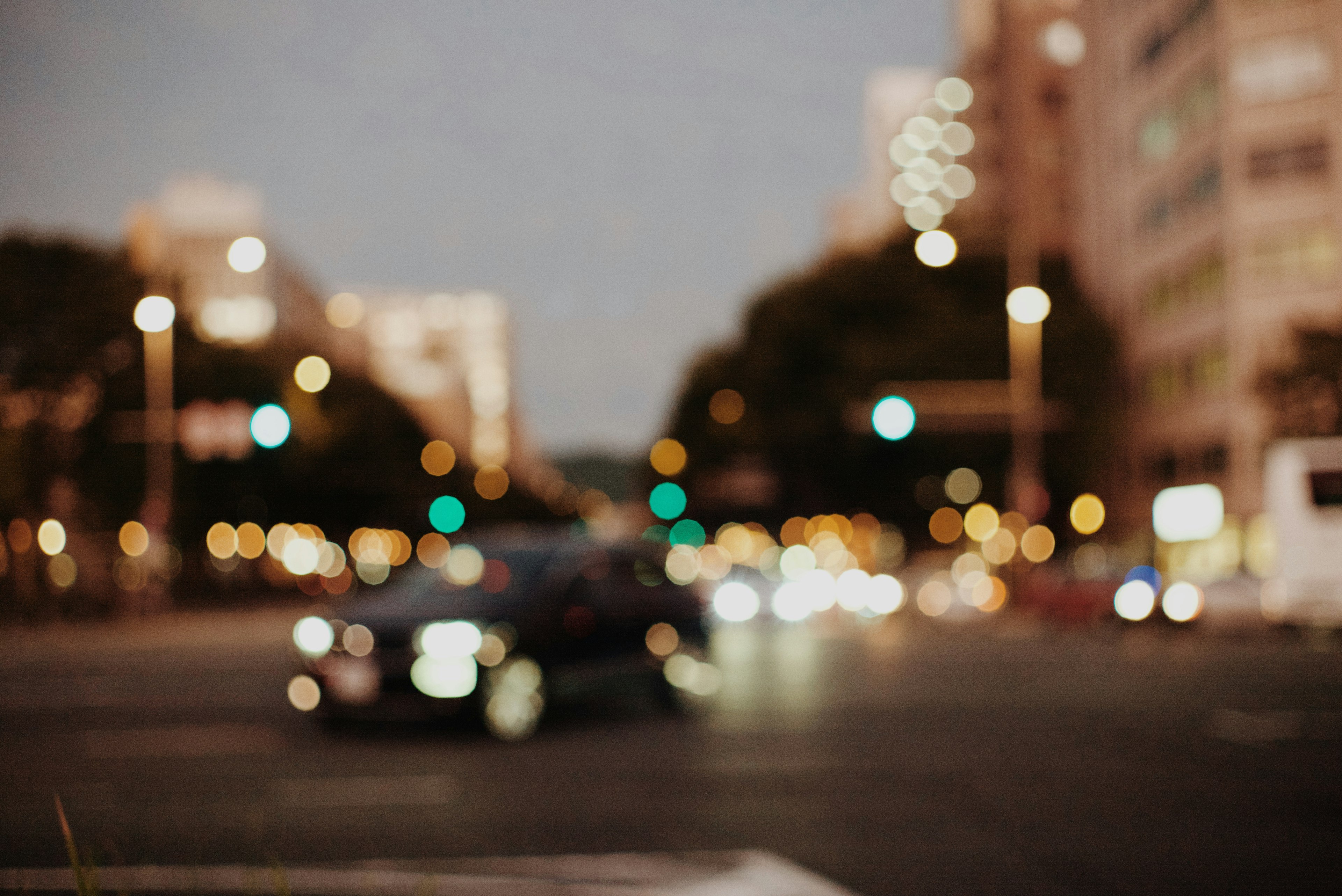 Blurry nighttime city intersection with a black car and many lights