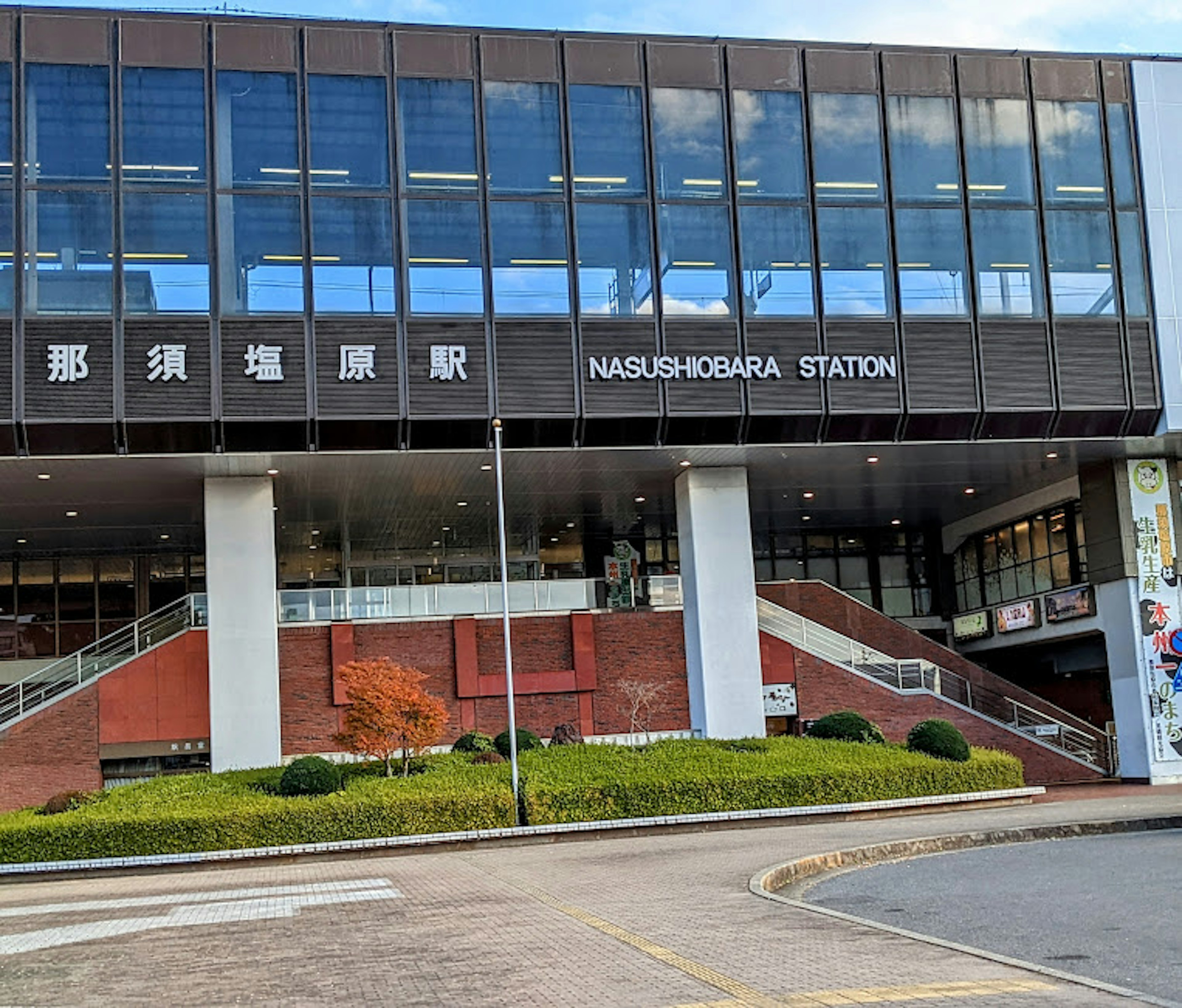 Vue extérieure de la gare de Nasushiobara avec le nom de la gare en anglais et en japonais