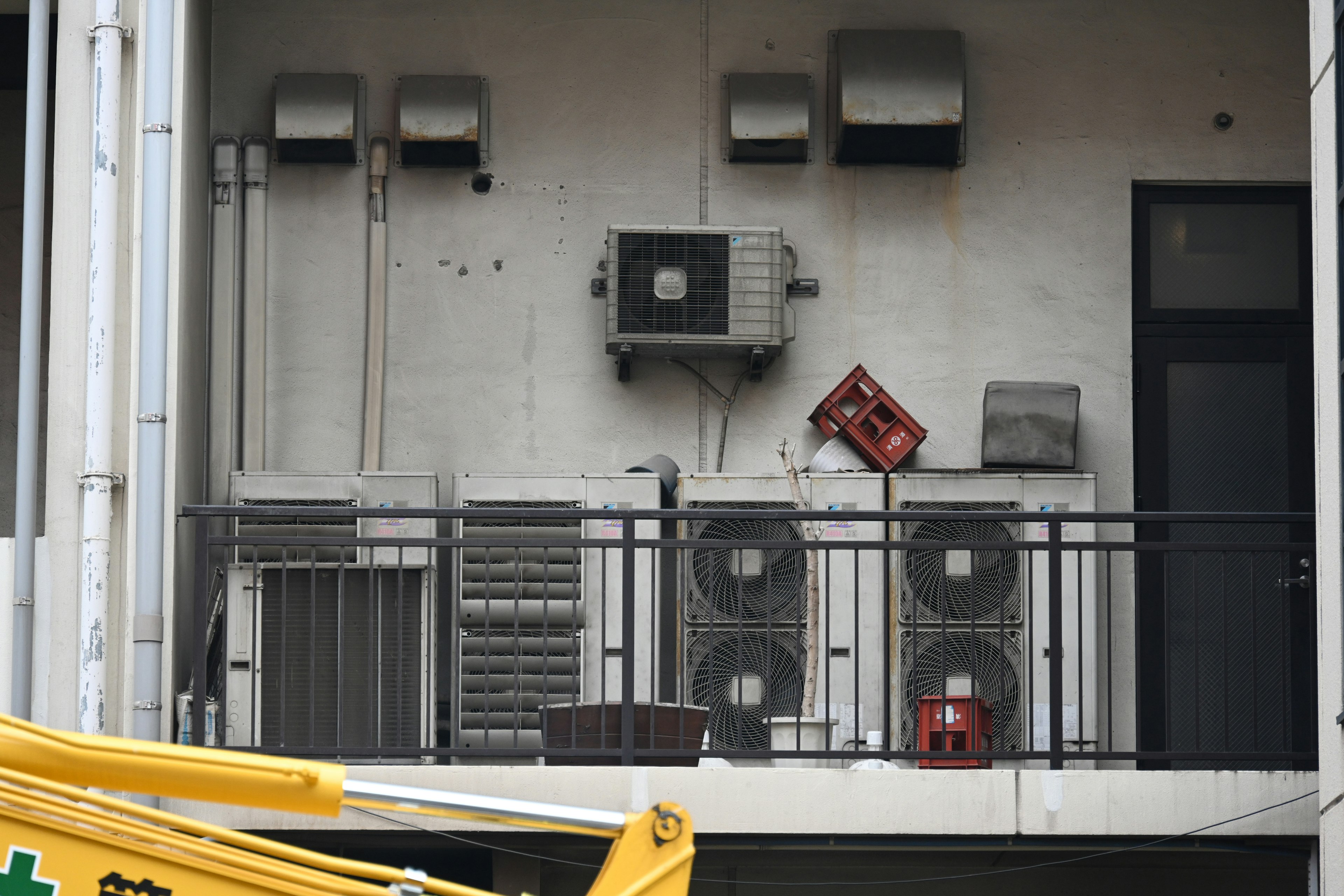 Exterior view of a balcony featuring multiple air conditioning units and piping