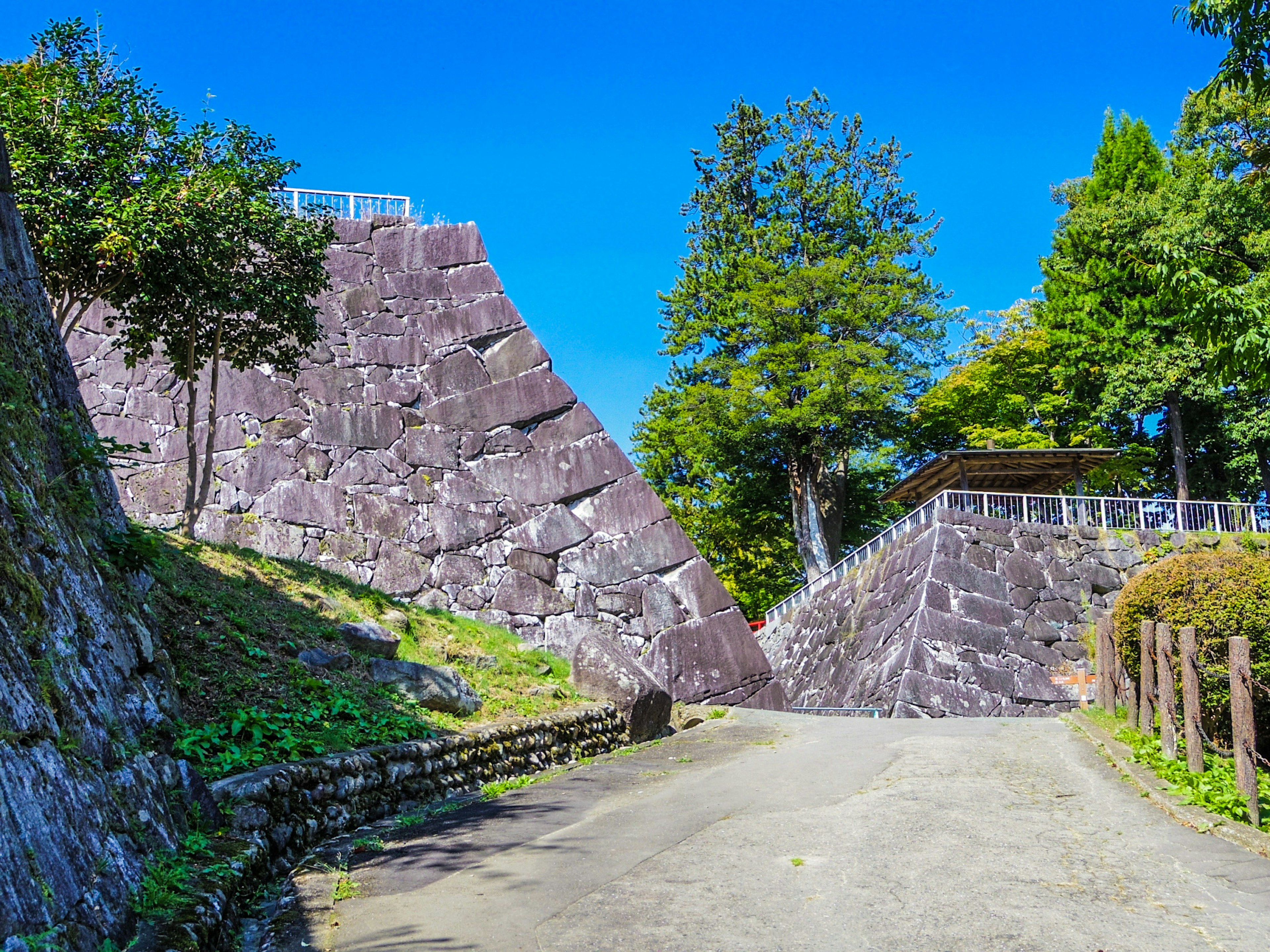 Muros de castillo de piedra bajo un cielo azul claro con árboles verdes