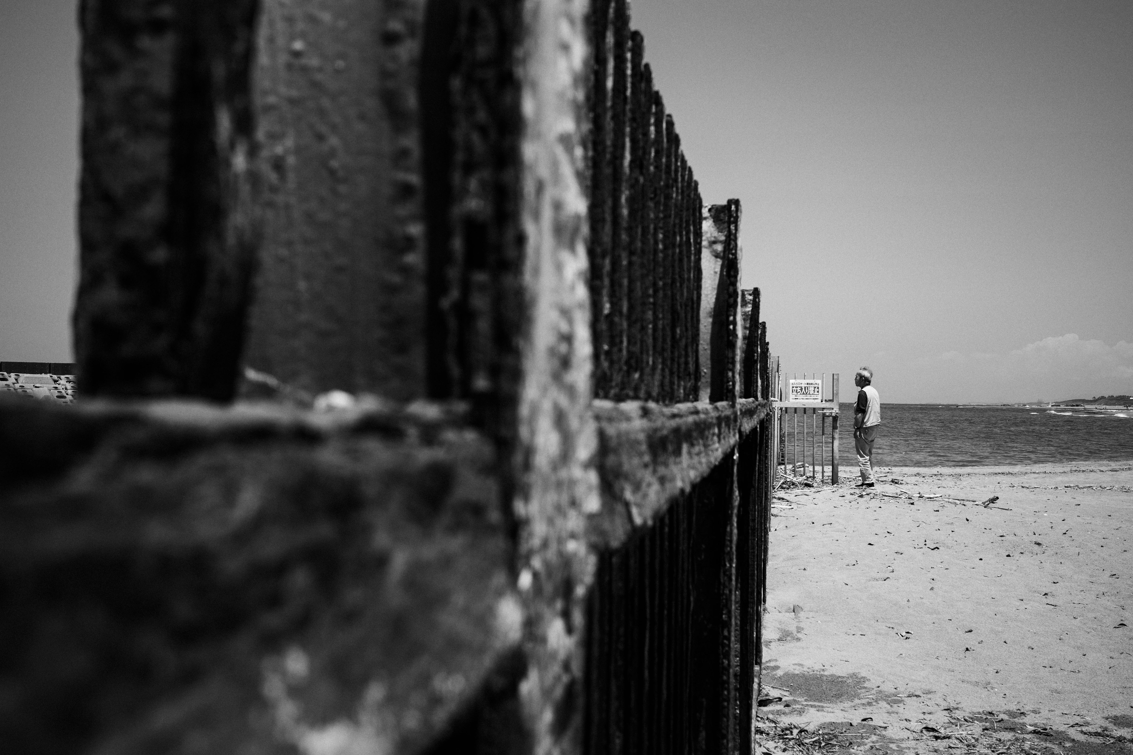 Imagen en blanco y negro de una cerca de playa con la silueta de una persona