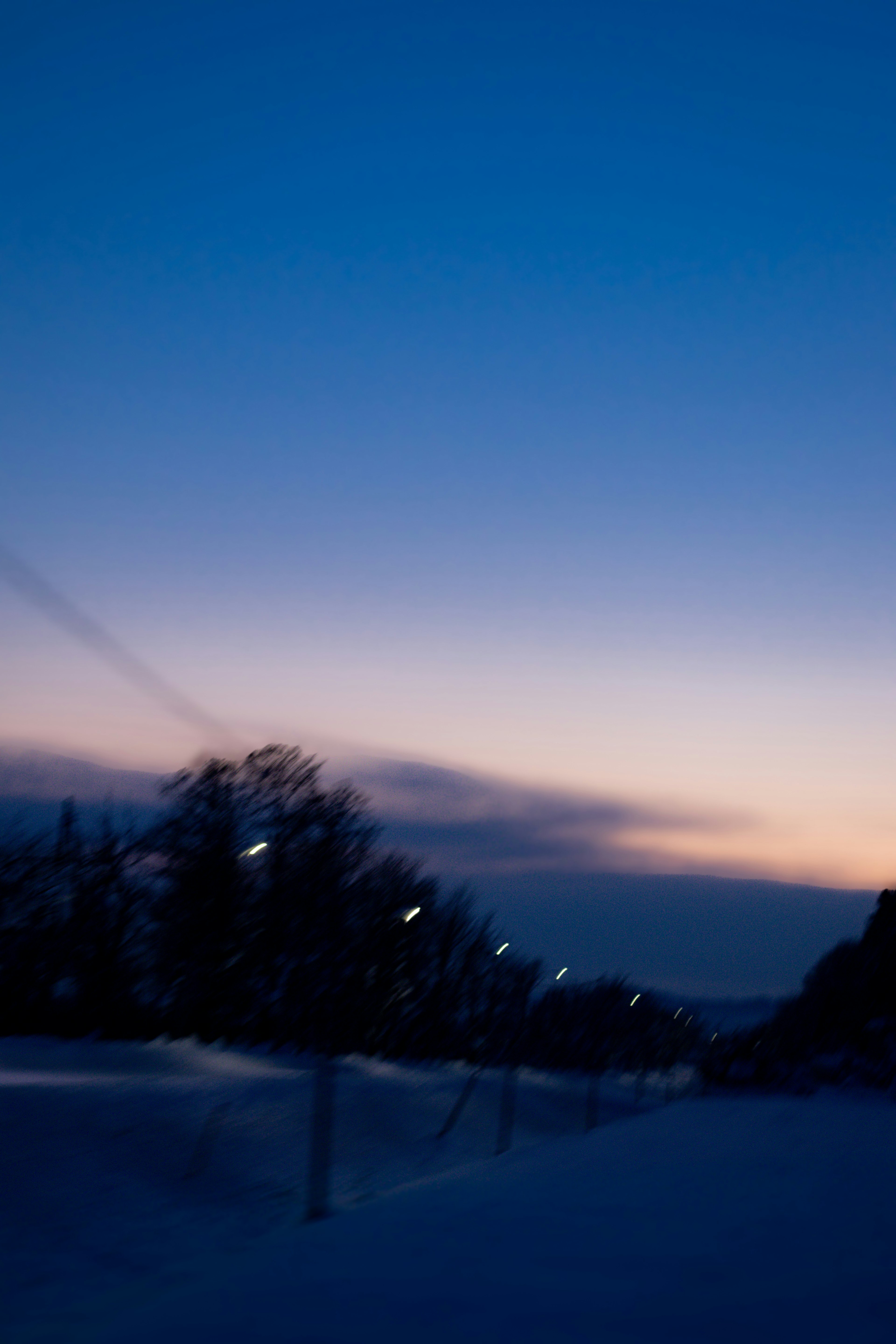 雪の中の夕暮れの風景　青い空とオレンジのグラデーション　街灯が並ぶ道