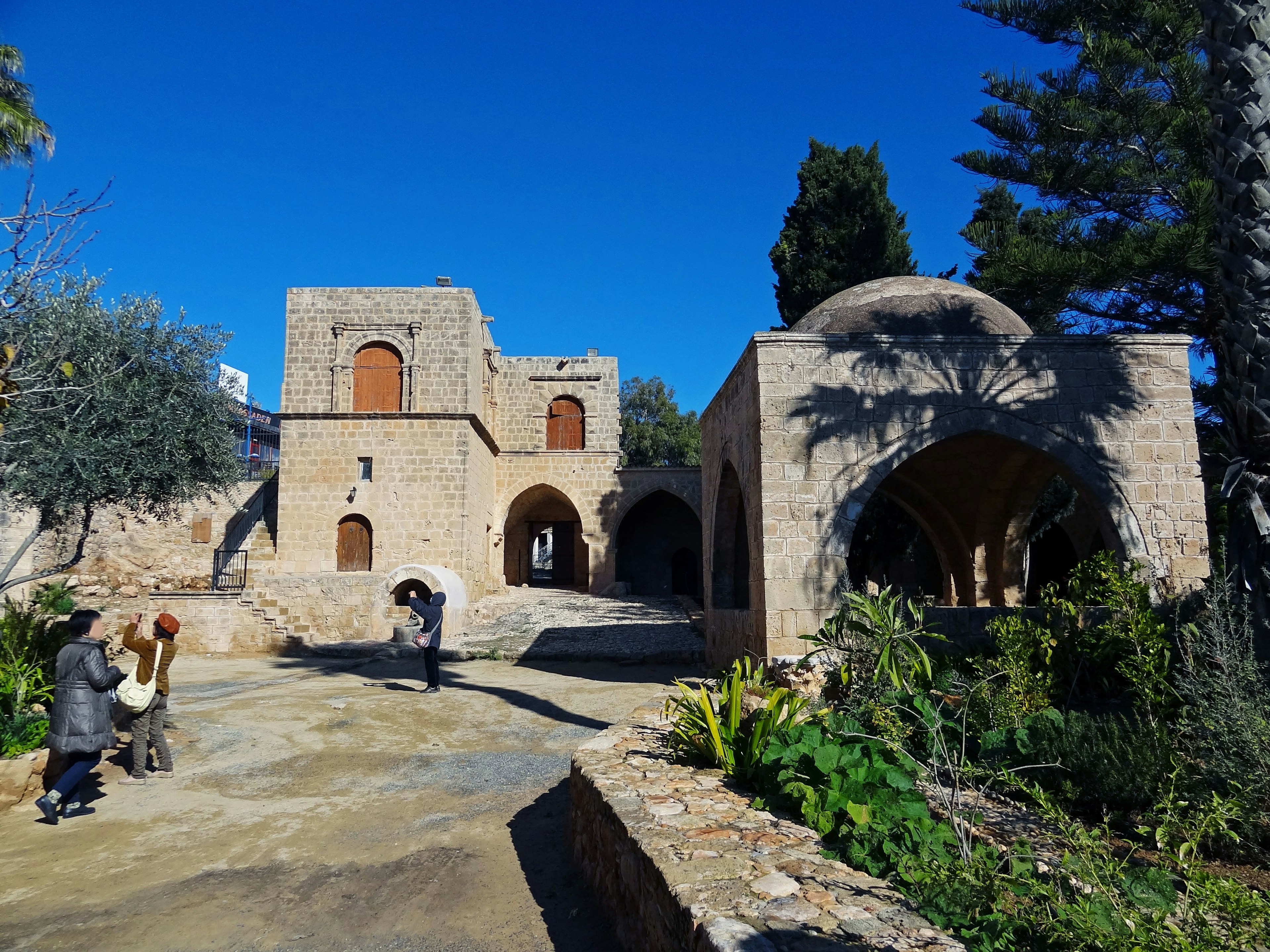 Historic stone buildings and garden under a blue sky