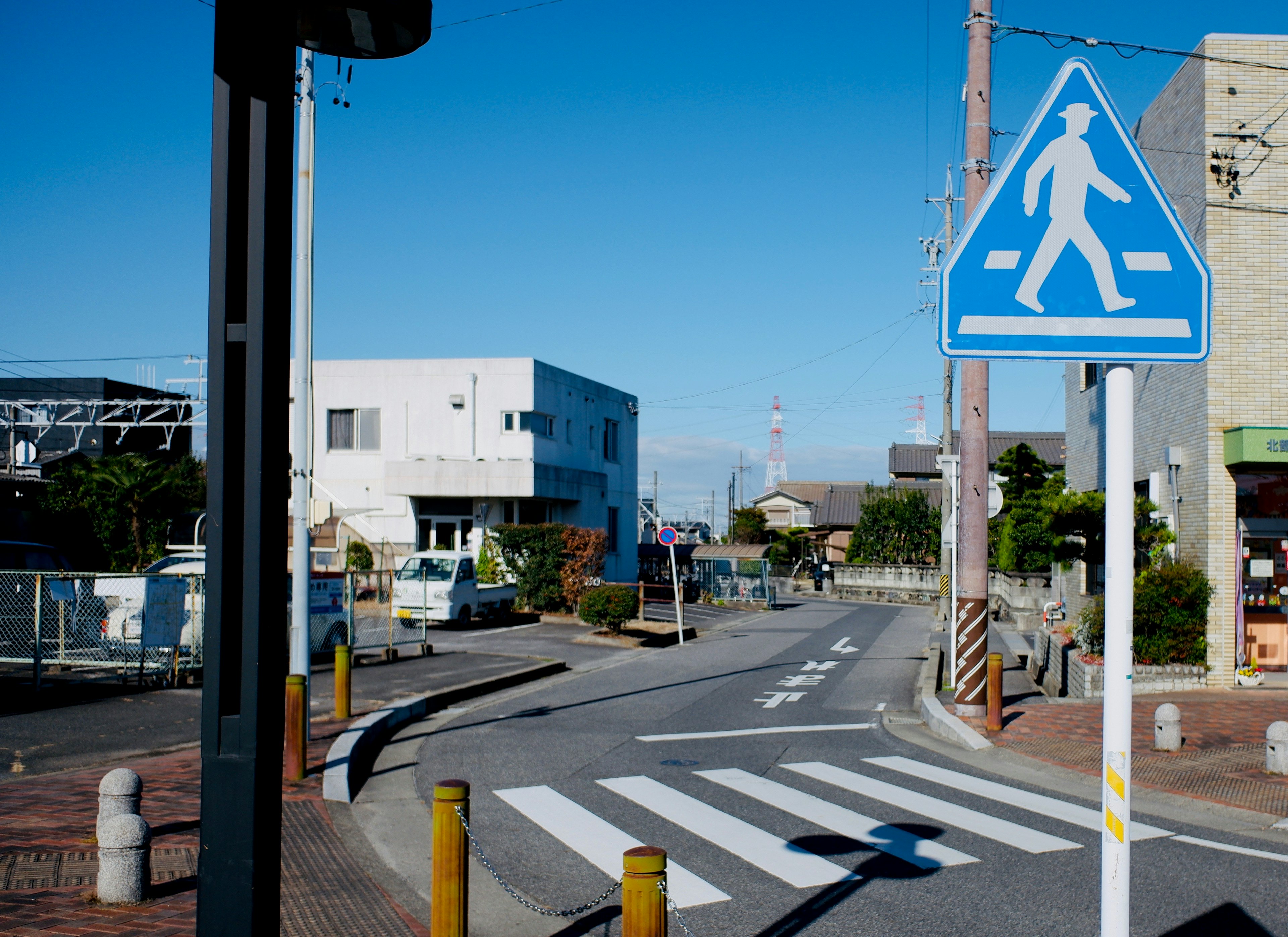 Vista di una strada tranquilla con un segnale pedonale blu e un attraversamento