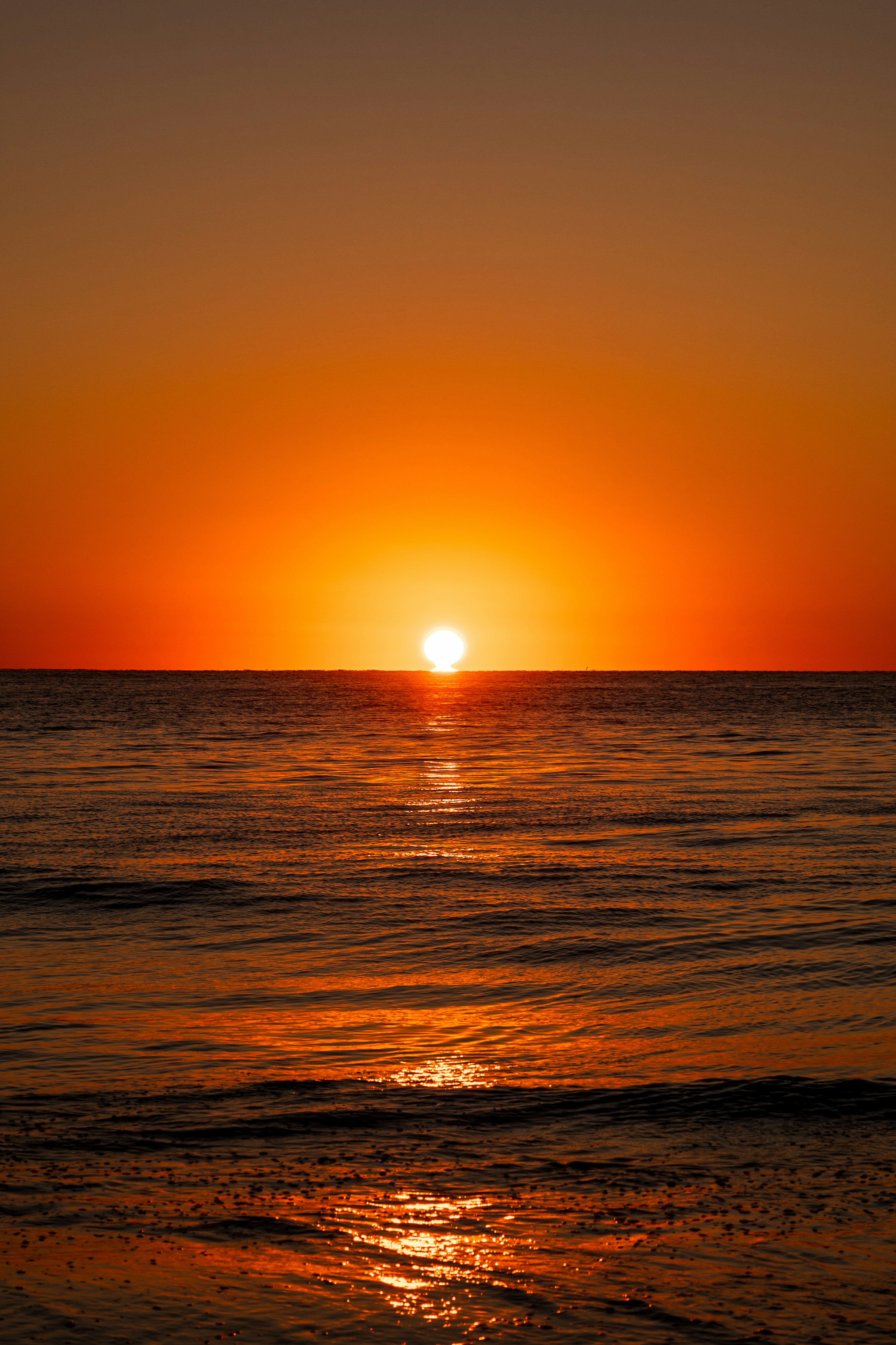 Bellissimo tramonto con tonalità arancioni su acque oceaniche calme