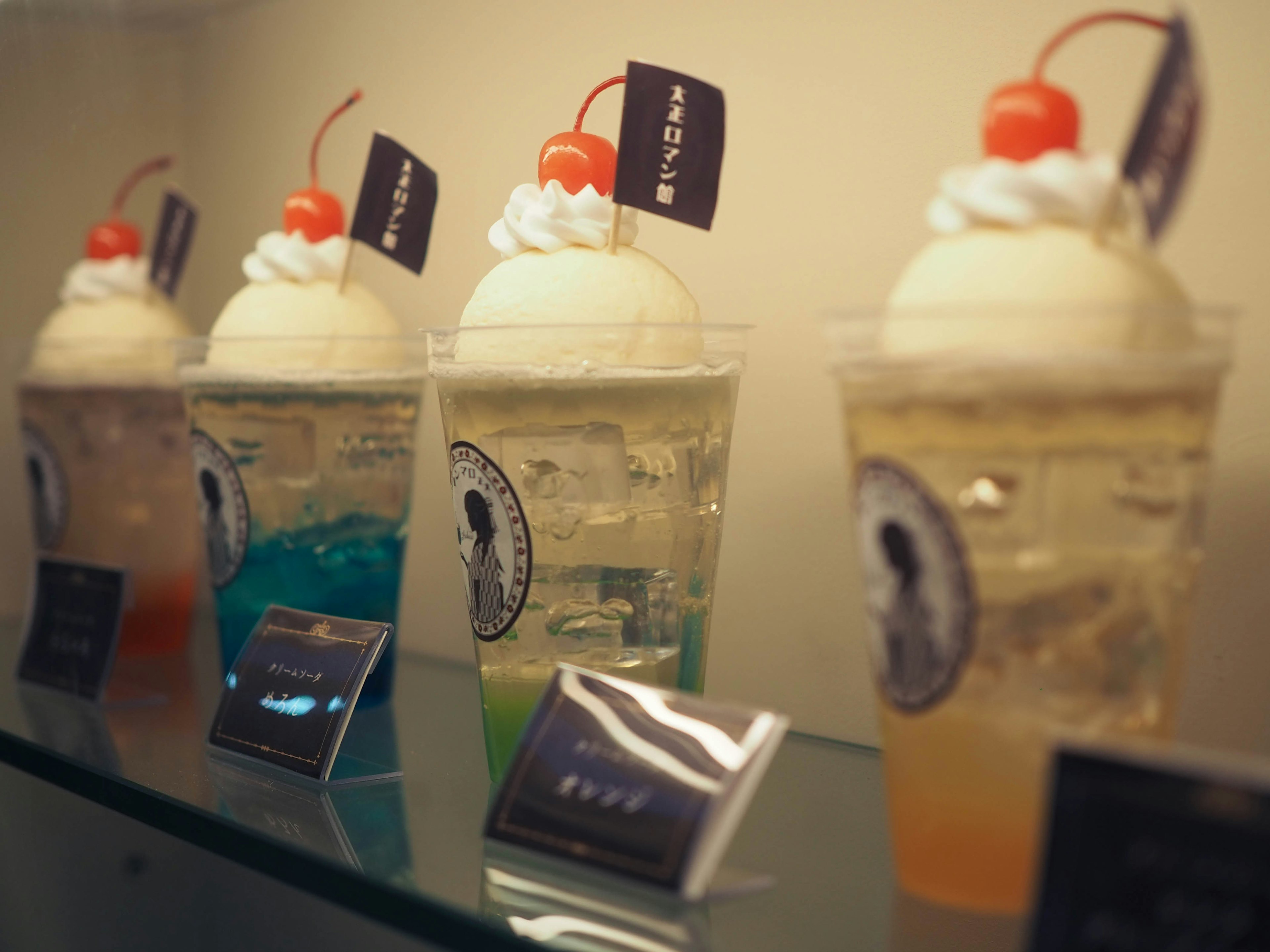 Colorful soda desserts with ice cream and cherries arranged in a display