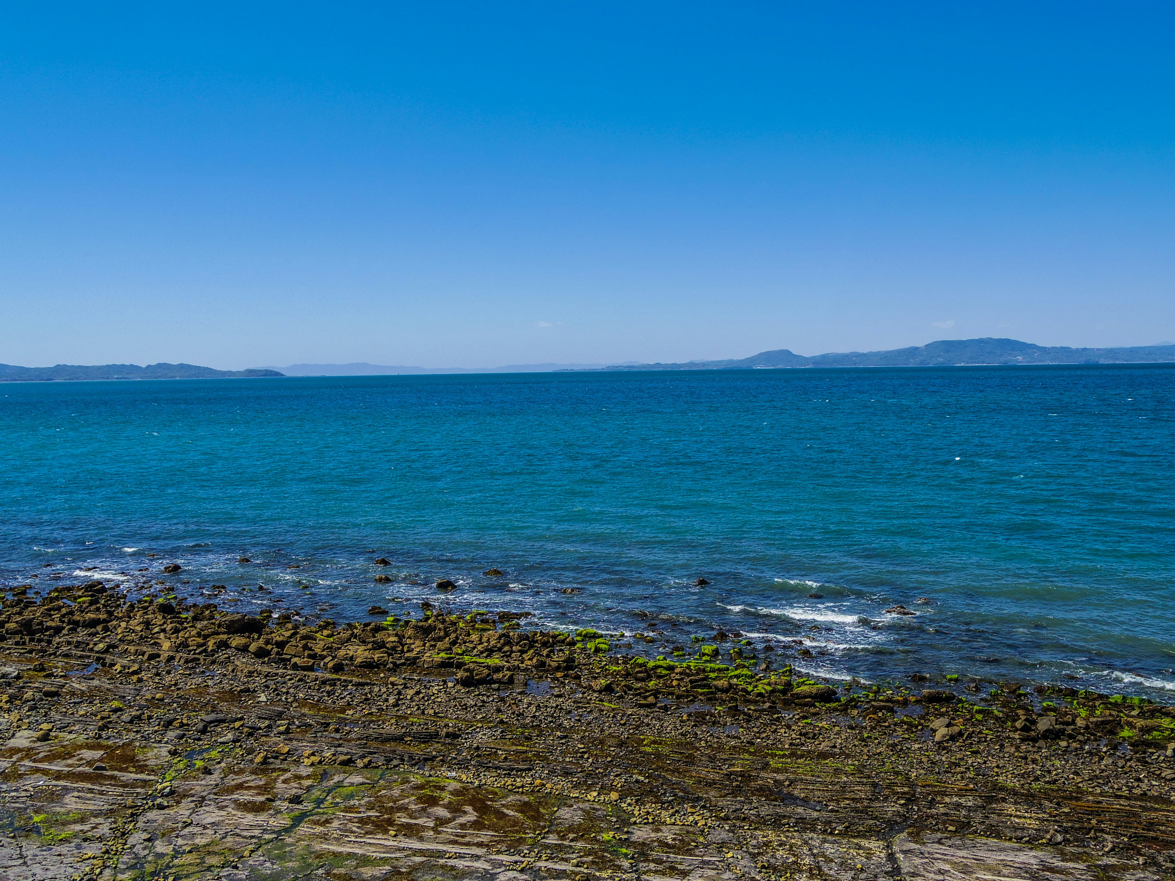 蓝色海洋和晴朗天空的风景 可见海岸岩石和海藻