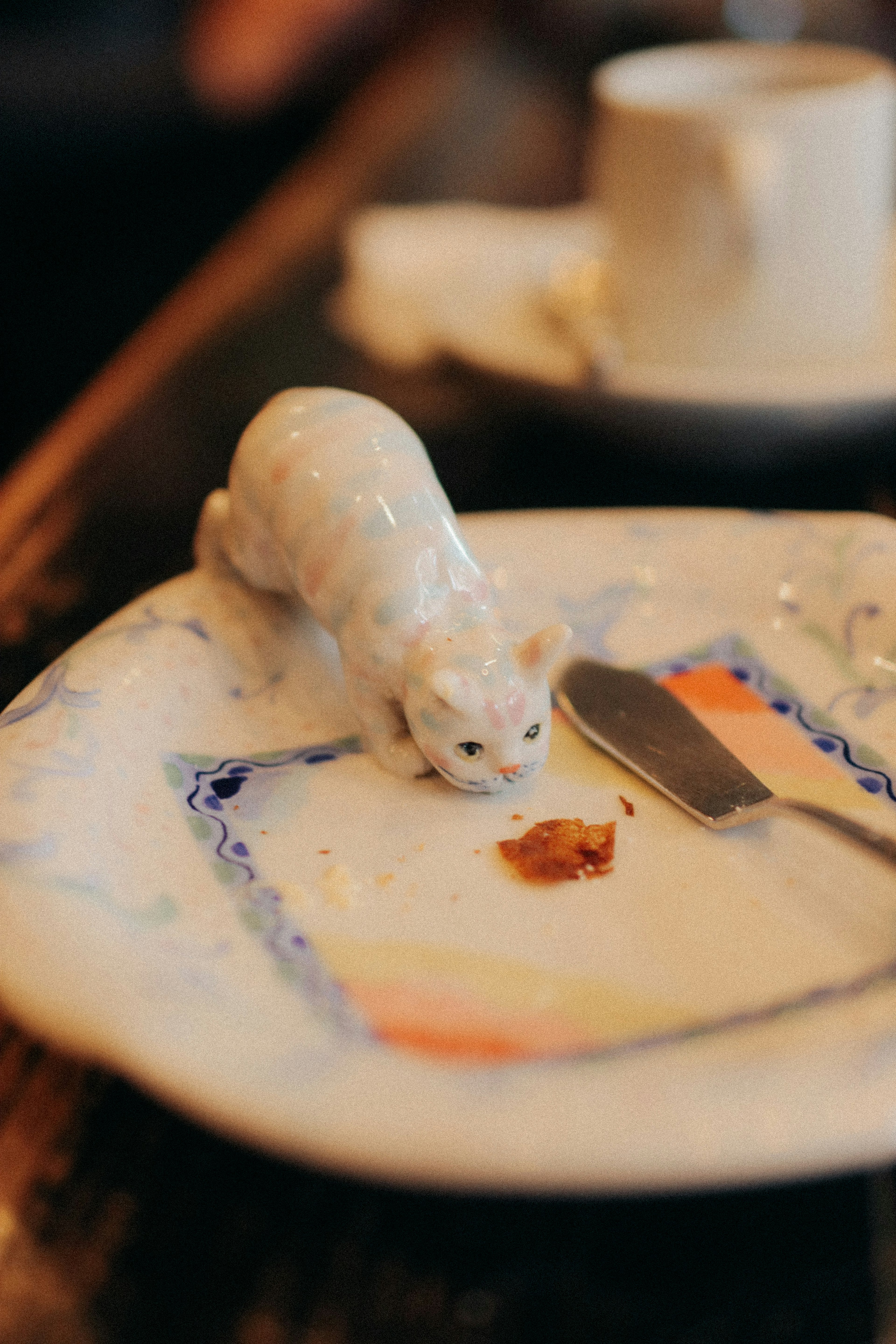 A white ceramic cat figurine on a plate with food remnants