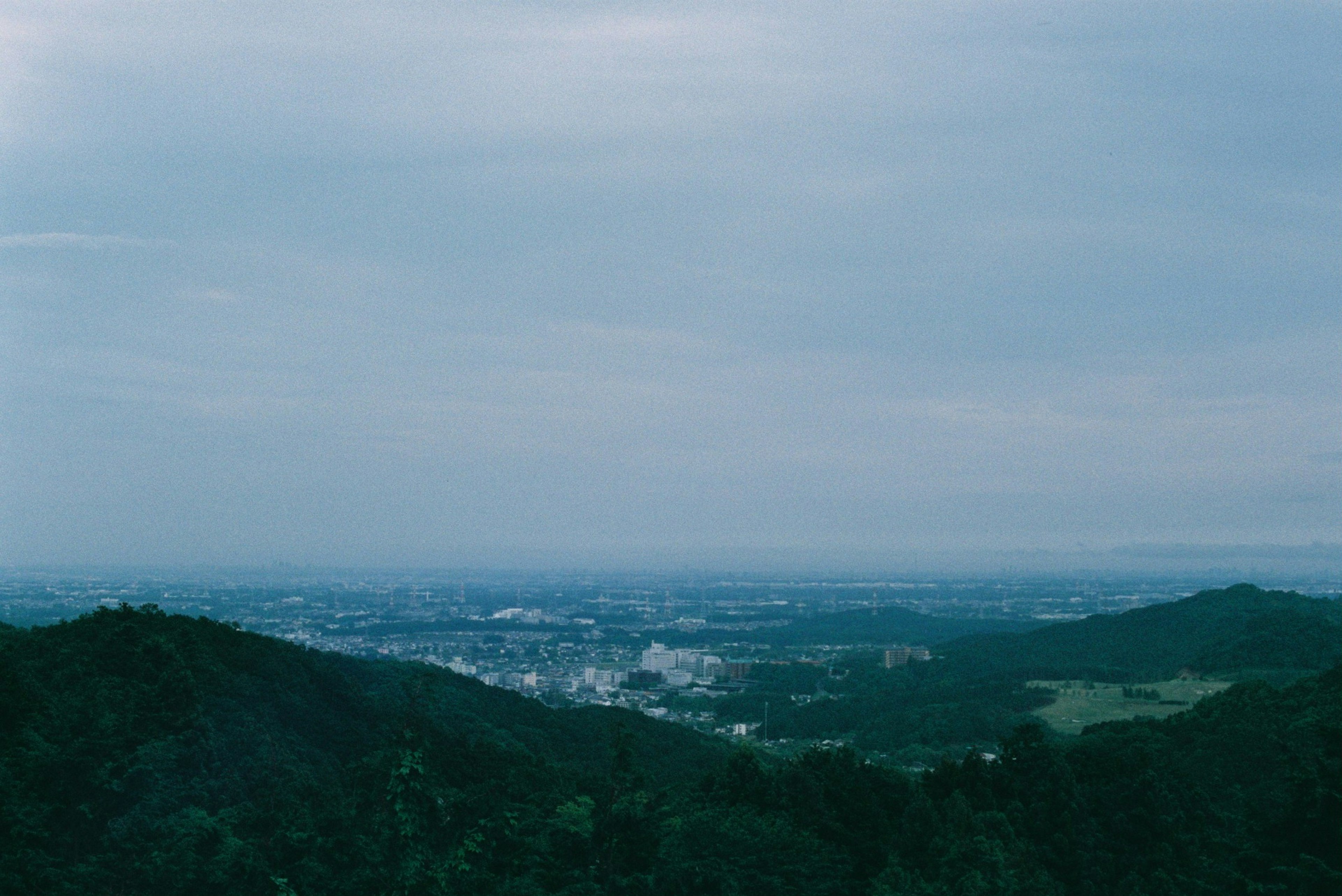 Mountain landscape with a view of a city under a blue sky and clouds