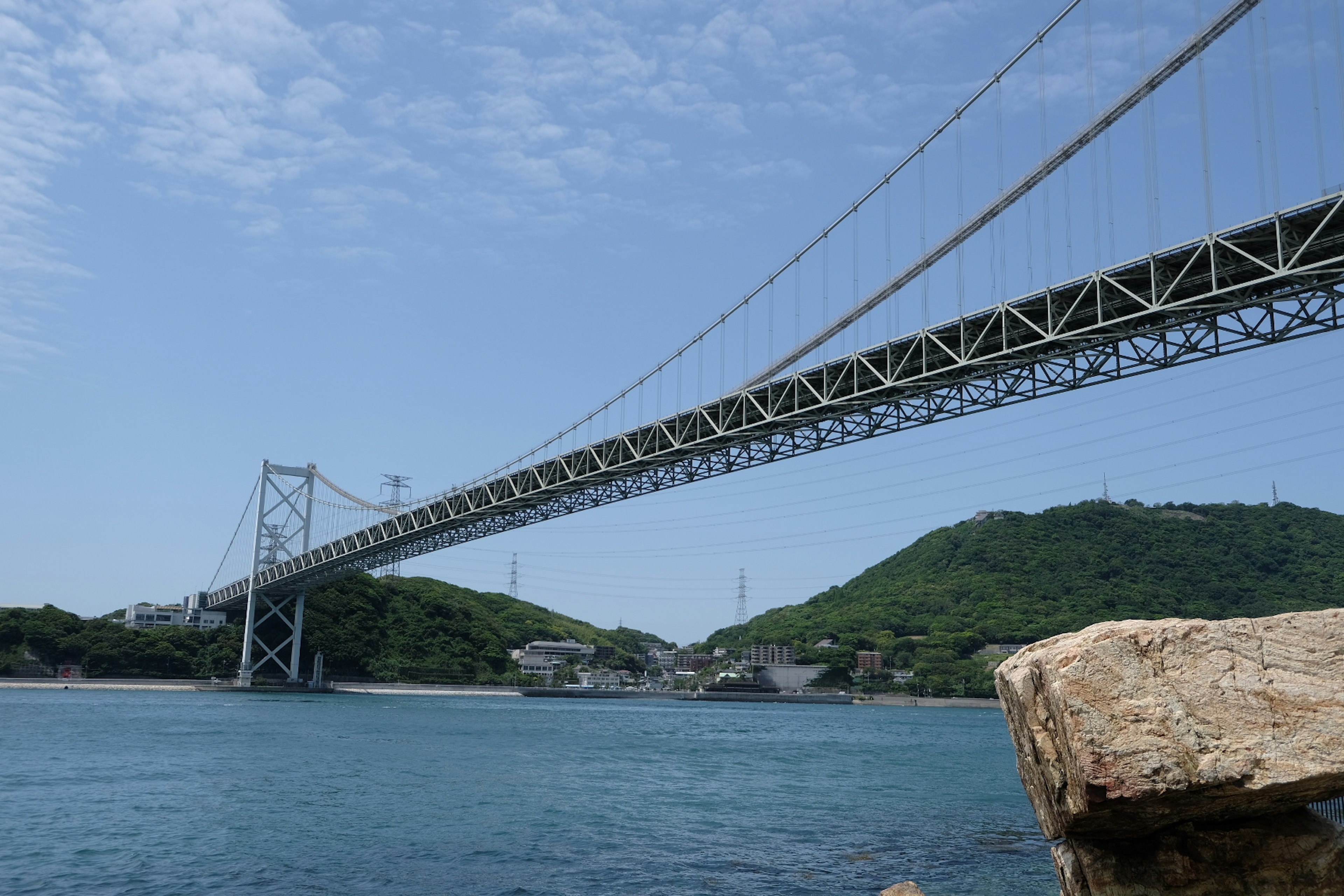 A beautiful bridge spanning across water under a blue sky with green hills in the background