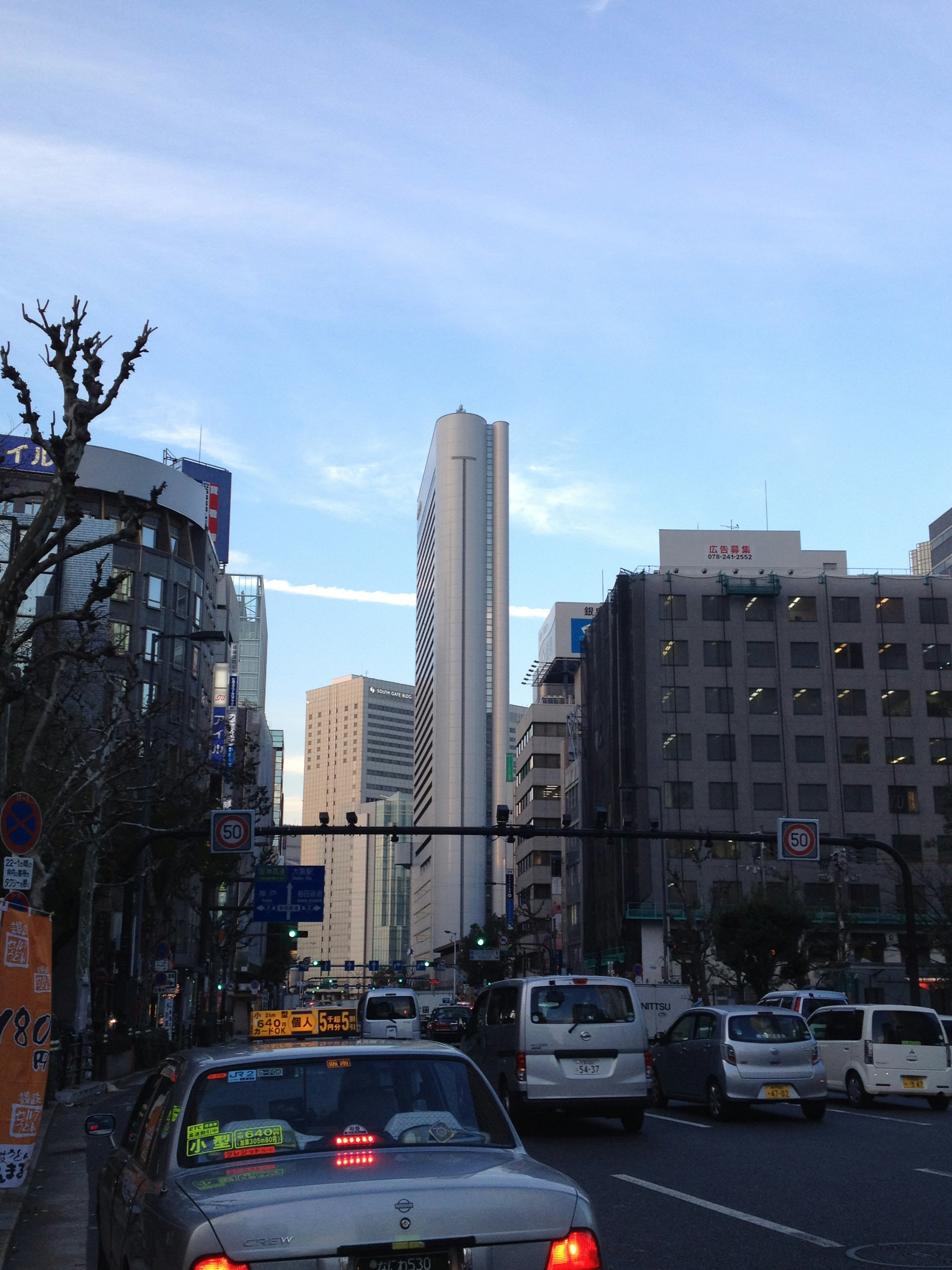 Paisaje urbano con un rascacielos calle concurrida con coches cielo azul y nubes