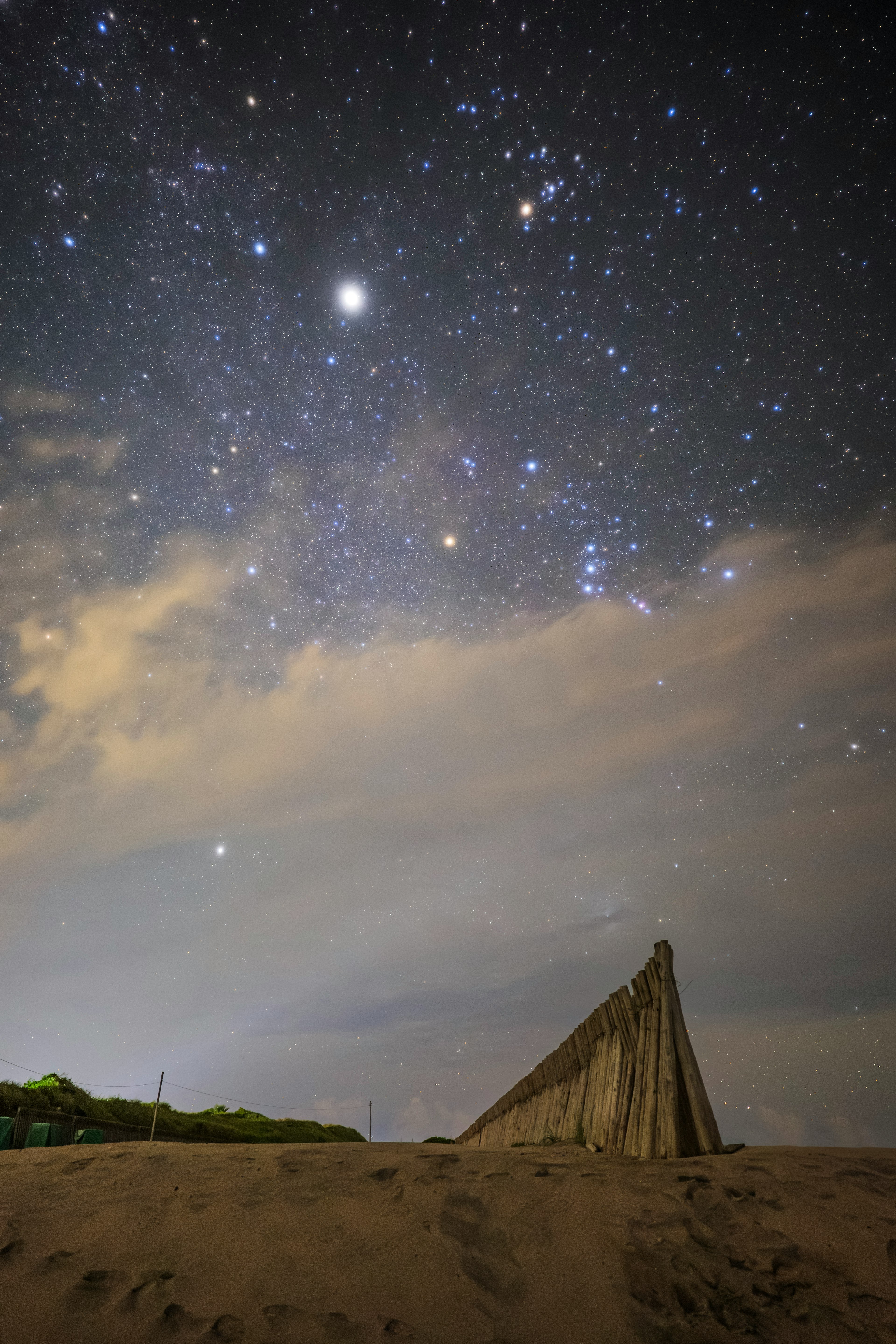 Ciel nocturne étoilé au-dessus d'une formation rocheuse pointue et d'un paysage sablonneux