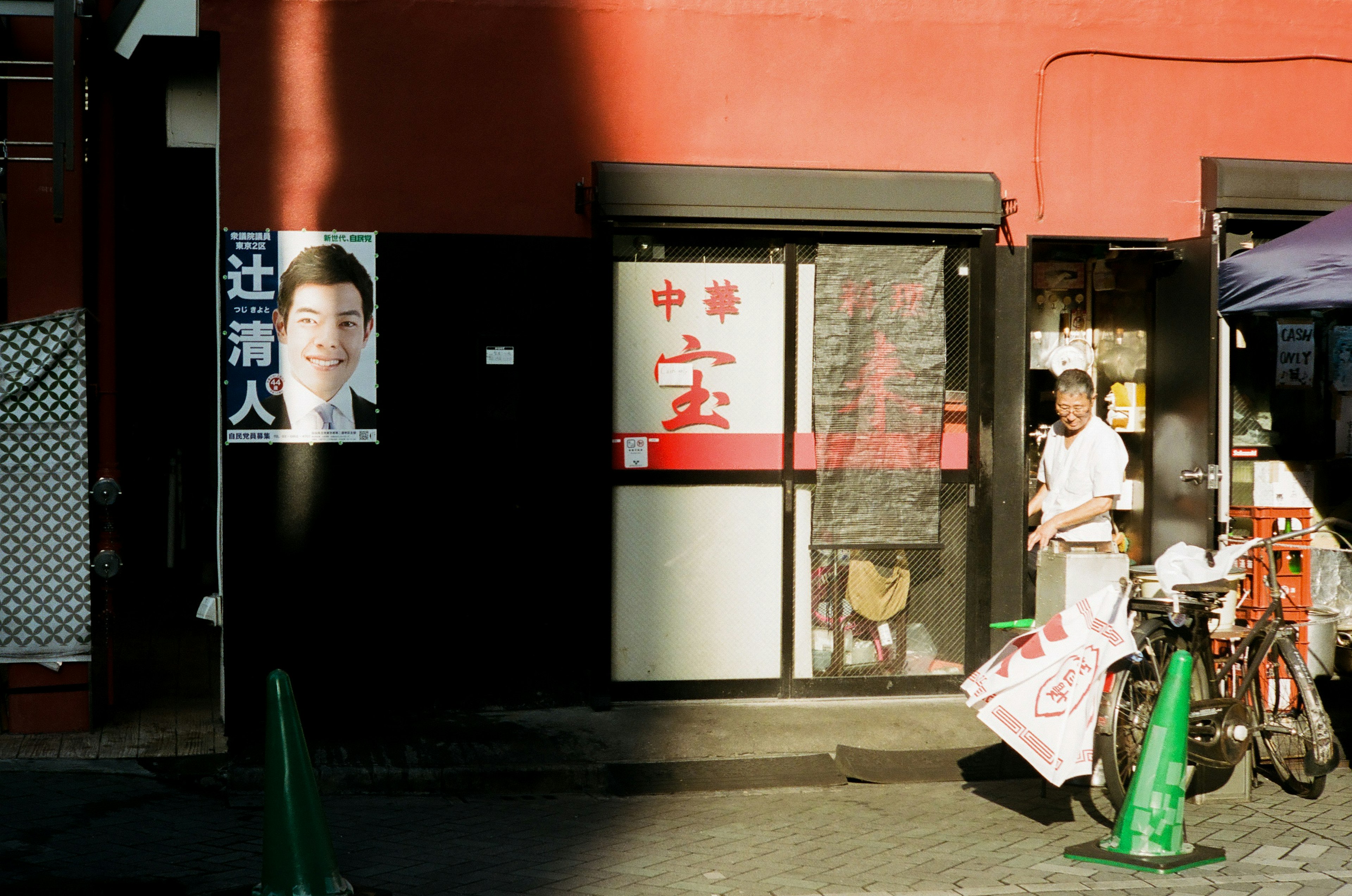 一個紅色牆壁的店面，帶有中餐館招牌和一個在外面的人