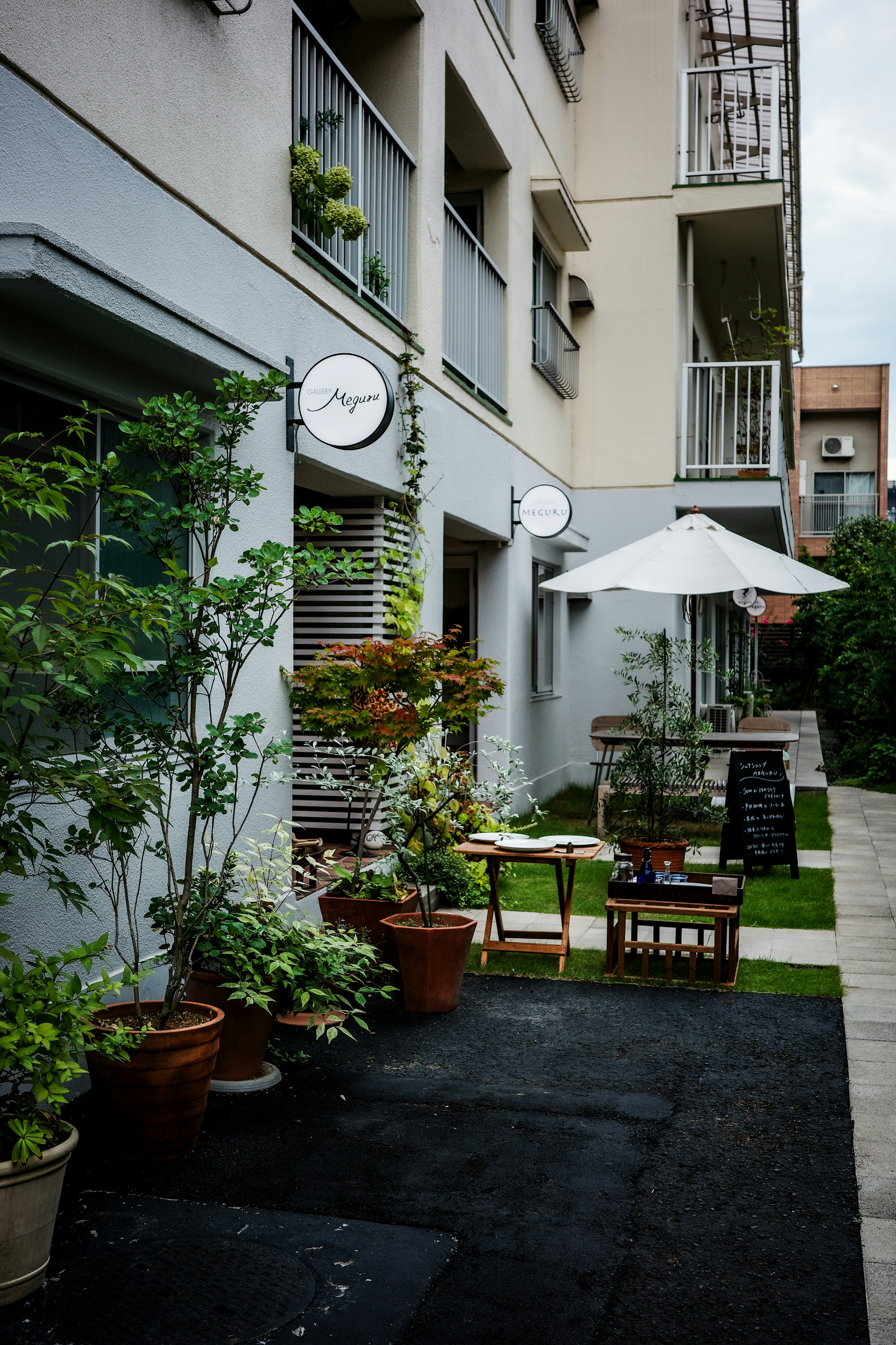 Charmantes Café-Außenansicht mit Grün und überdachter Terrasse