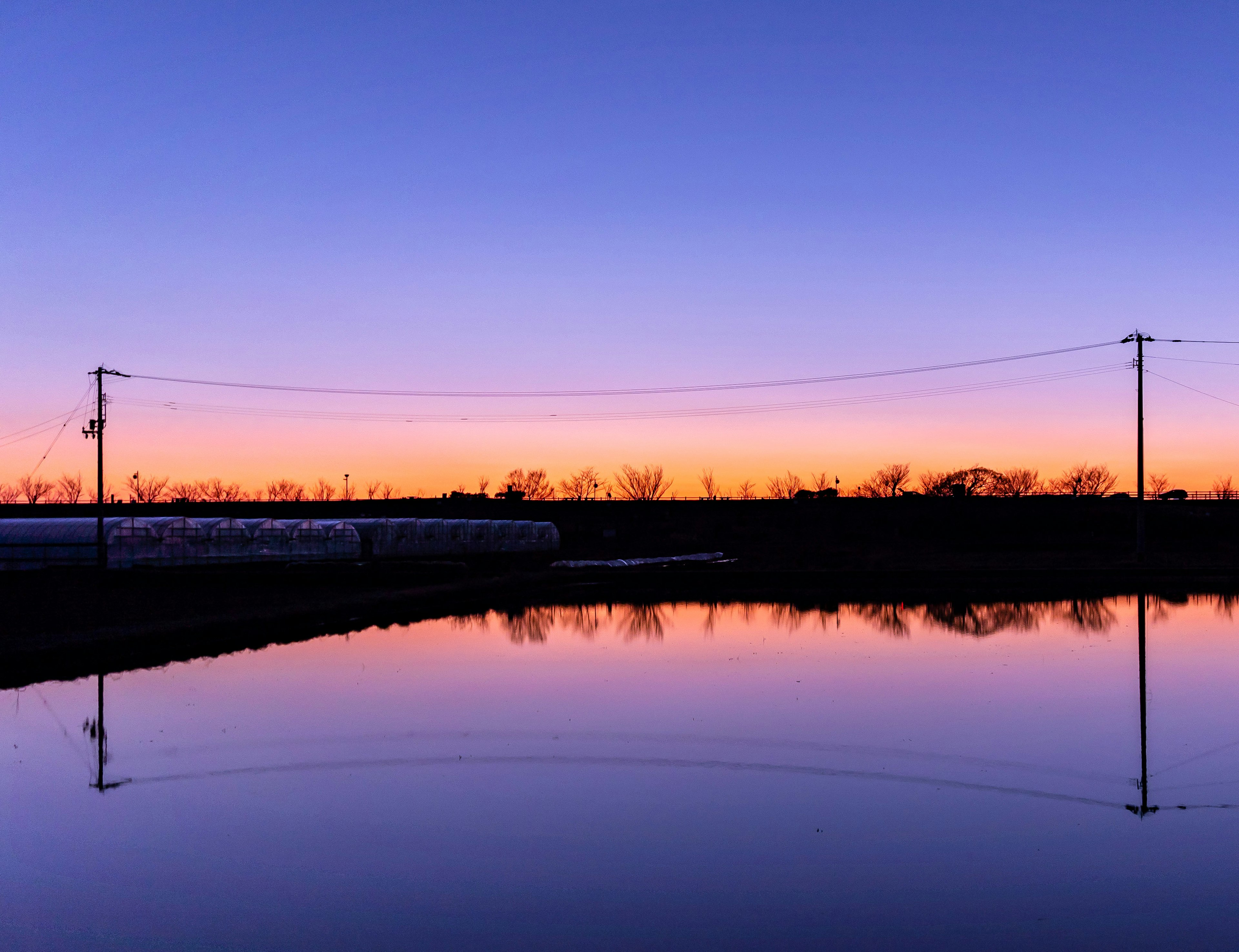 美しい夕焼けの空が水面に映る風景 電線とシルエットが特徴的