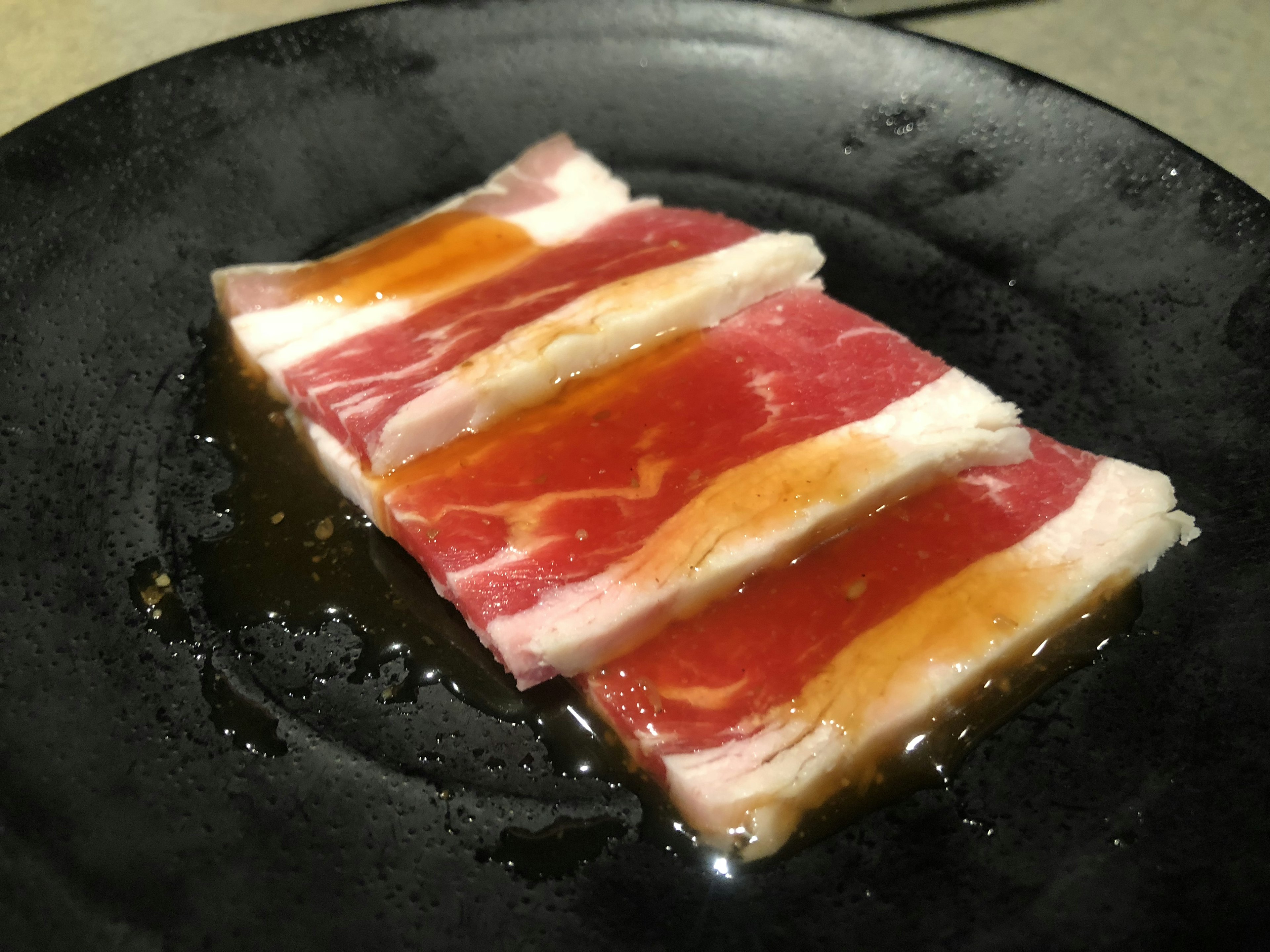 Viande tranchée disposée sur une assiette noire avec des couches colorées