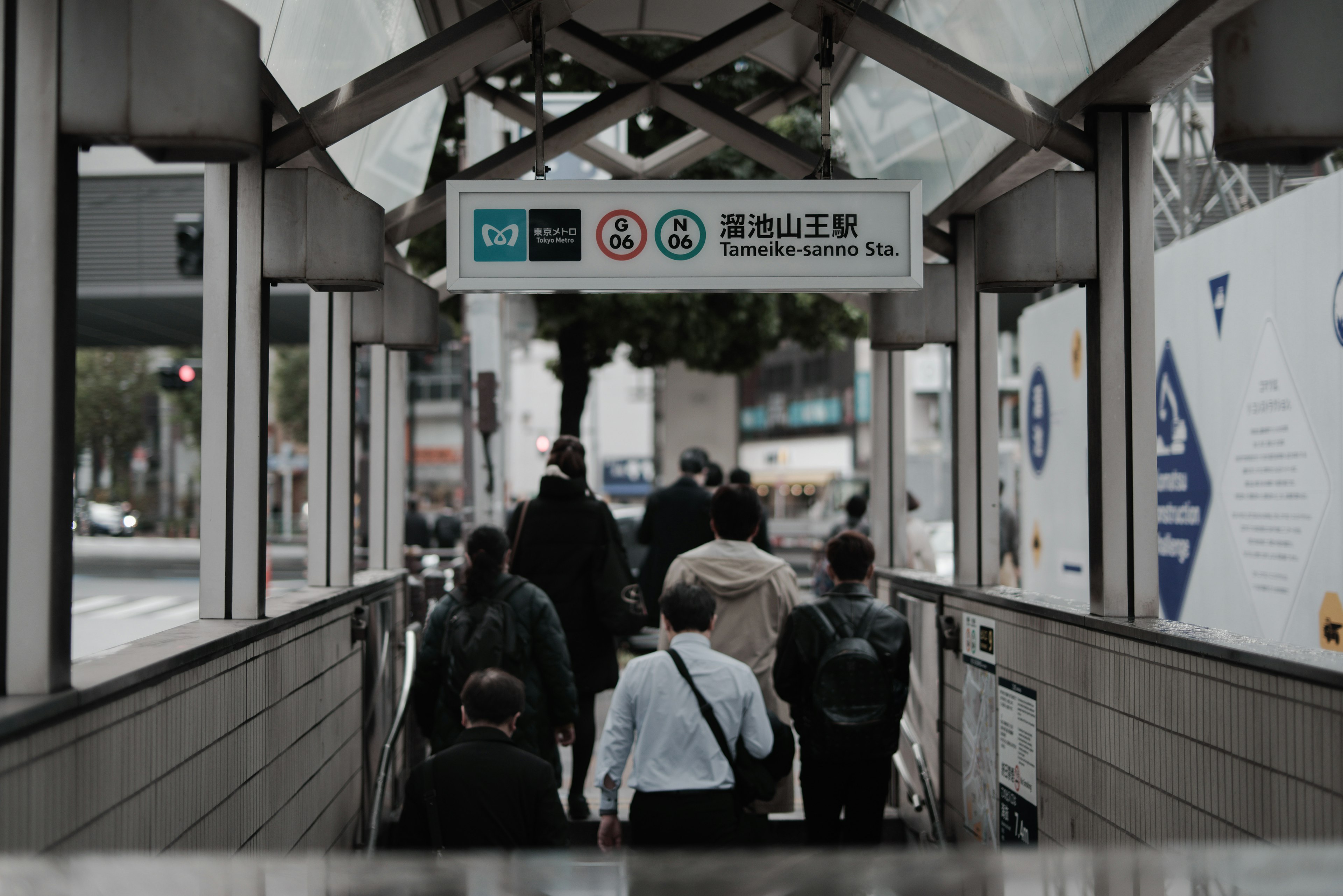 People walking towards a station with signs indicating directions