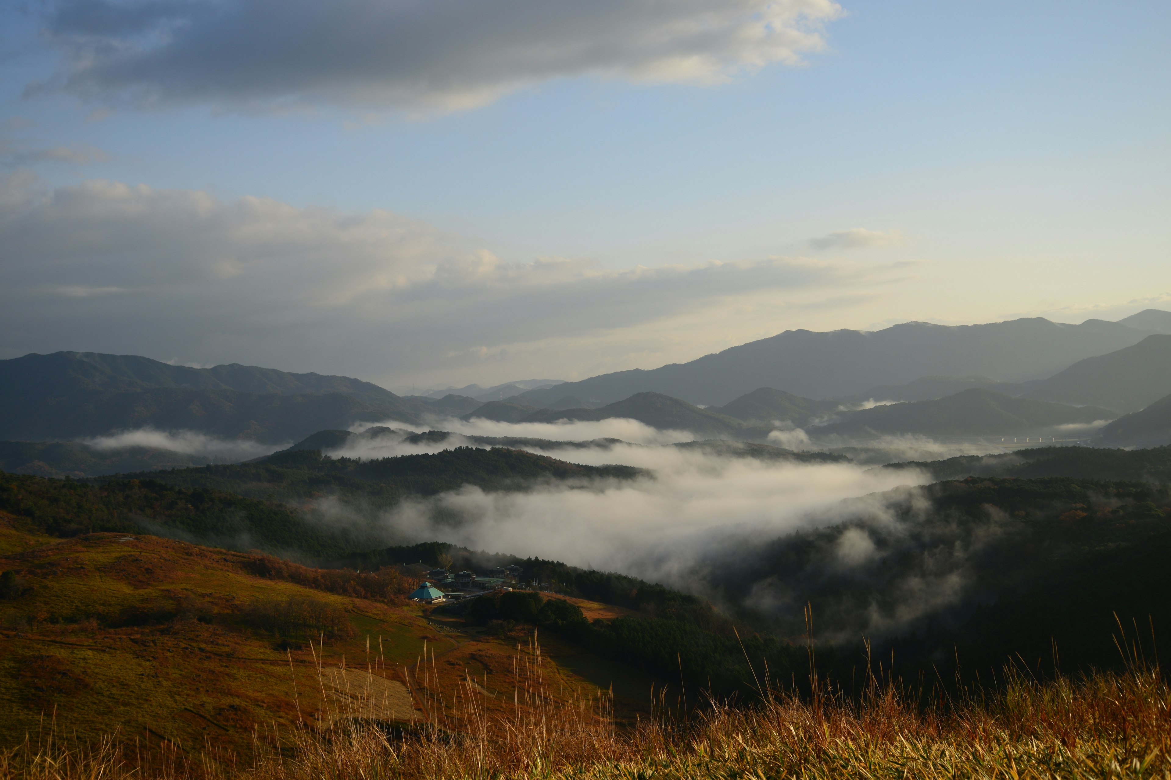 ทิวทัศน์ที่สวยงามของภูเขาและหุบเขาที่มีหมอกใต้ท้องฟ้าสีฟ้า